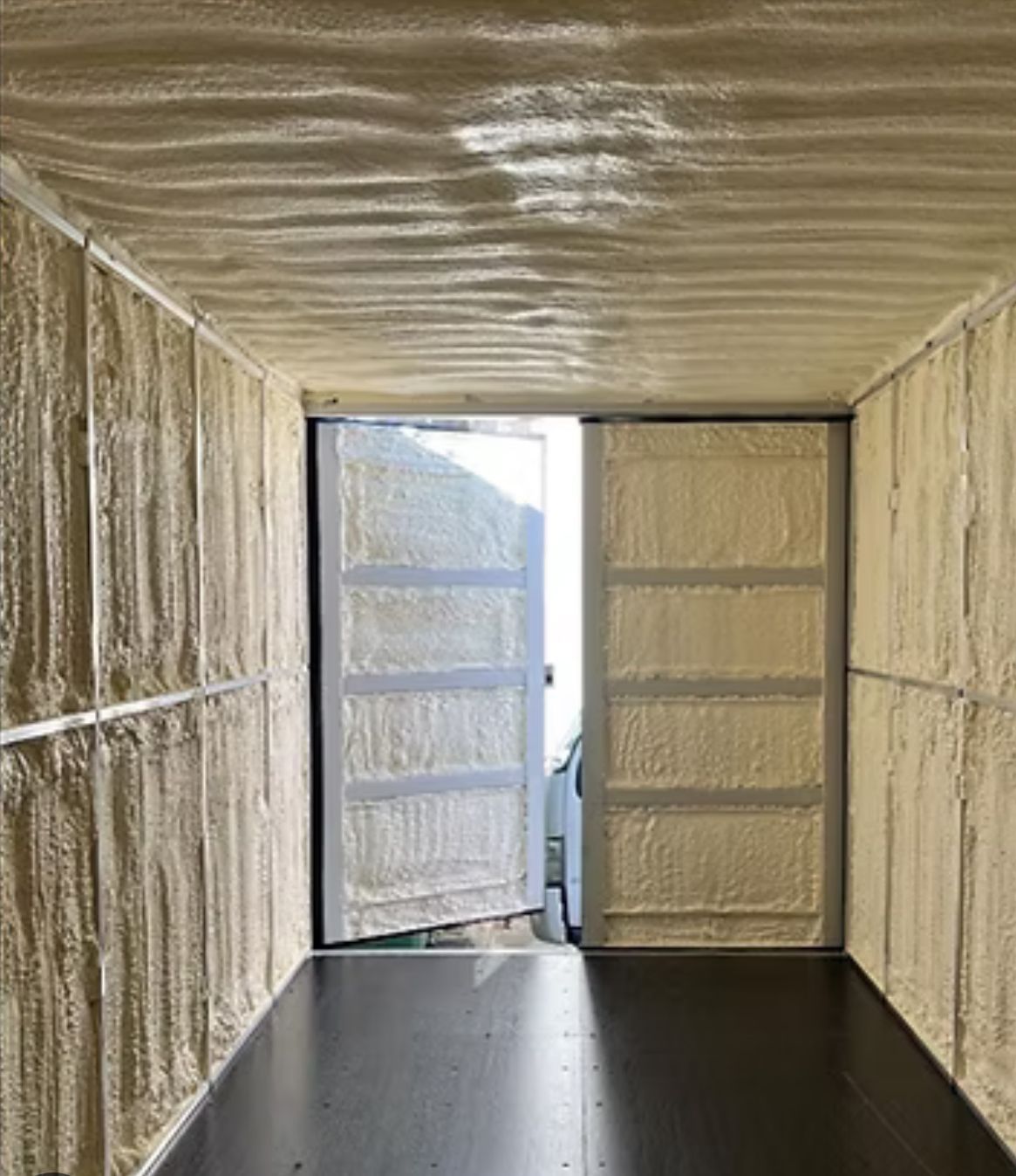 Interior of a shipping container with walls and doors covered in beige spray foam insulation, with open doors  — Proshield Insulation & Waterproofing In Shell Cove, NSW