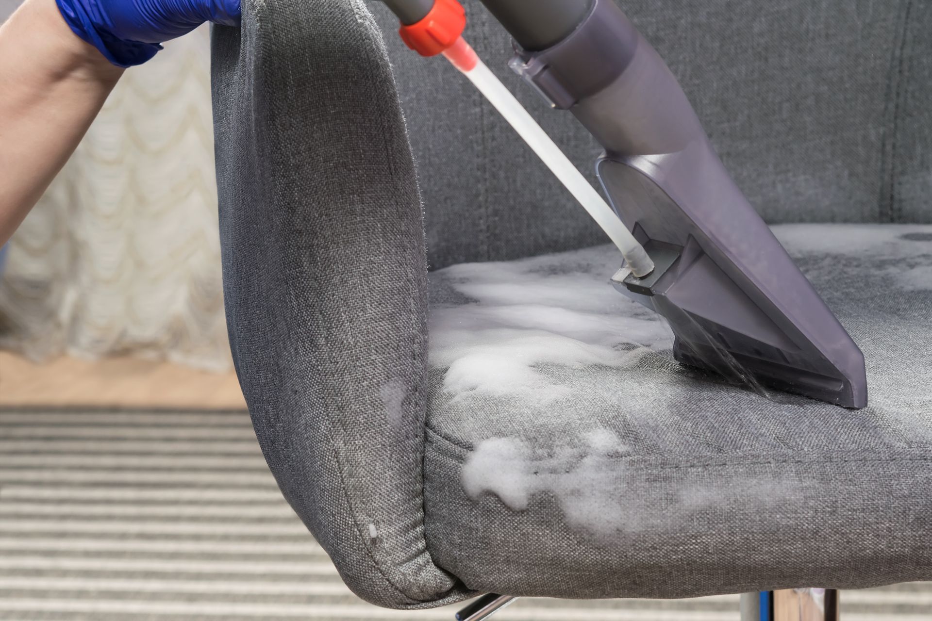 A person is cleaning a couch with a vacuum cleaner. — Durant, OK — James Dry Carpet & Upholstery Cleaning Service A person is cleaning a couch with a vacuum cleaner. — Durant, OK — James Dry Carpet & Upholstery Cleaning Service