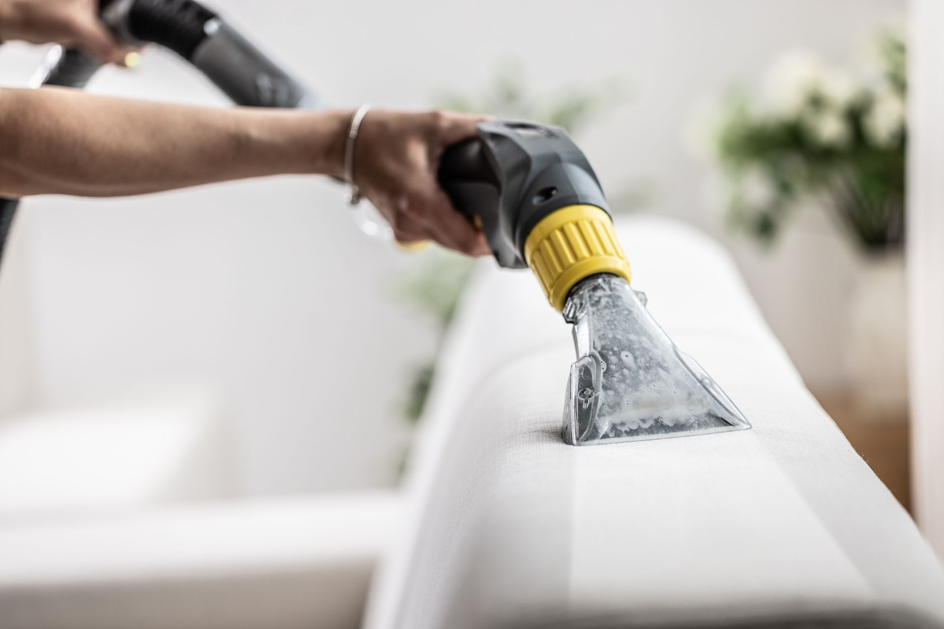 A person is cleaning a couch with a vacuum cleaner. — Durant, OK — James Dry Carpet & Upholstery Cleaning Service