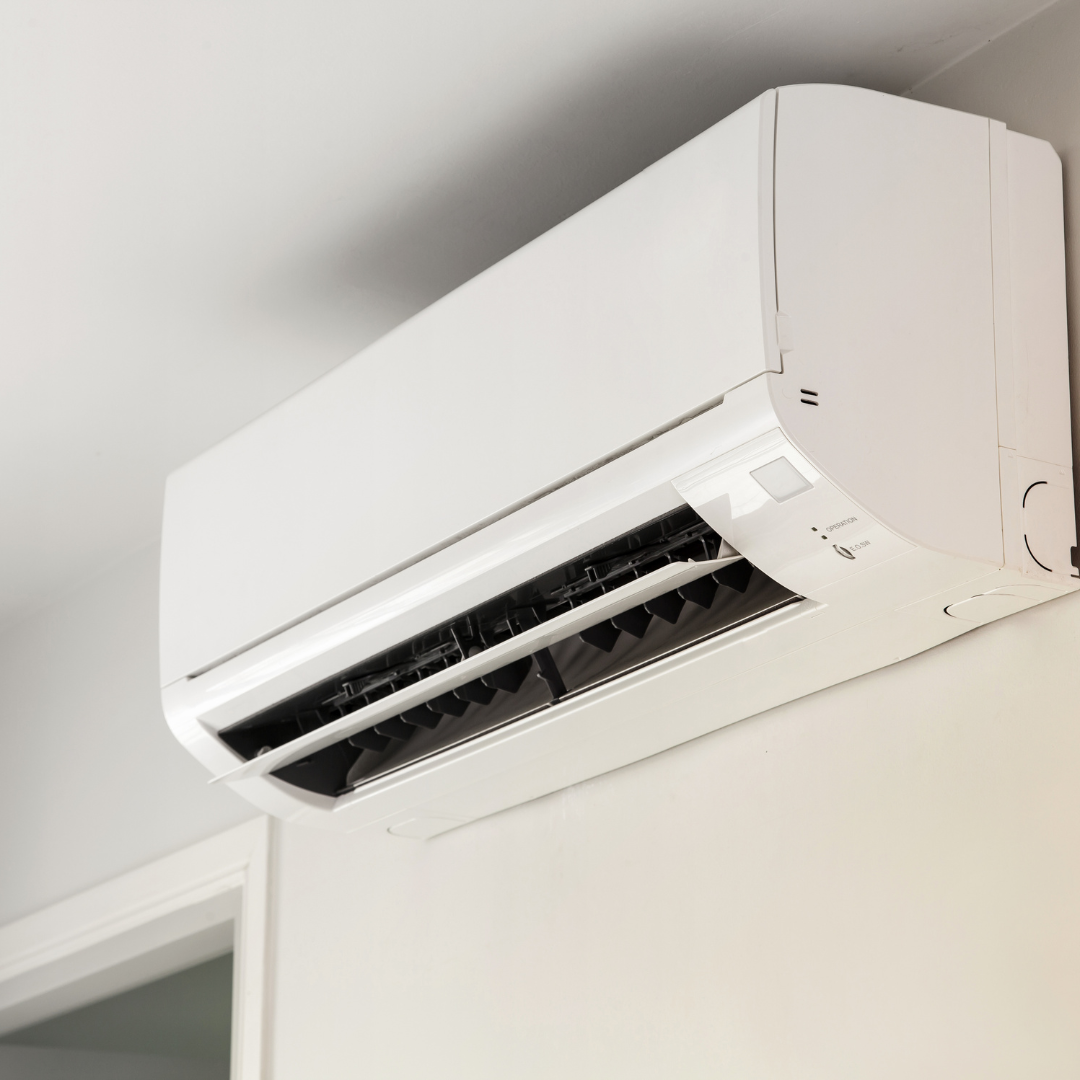 A white air conditioner is mounted on a white wall.