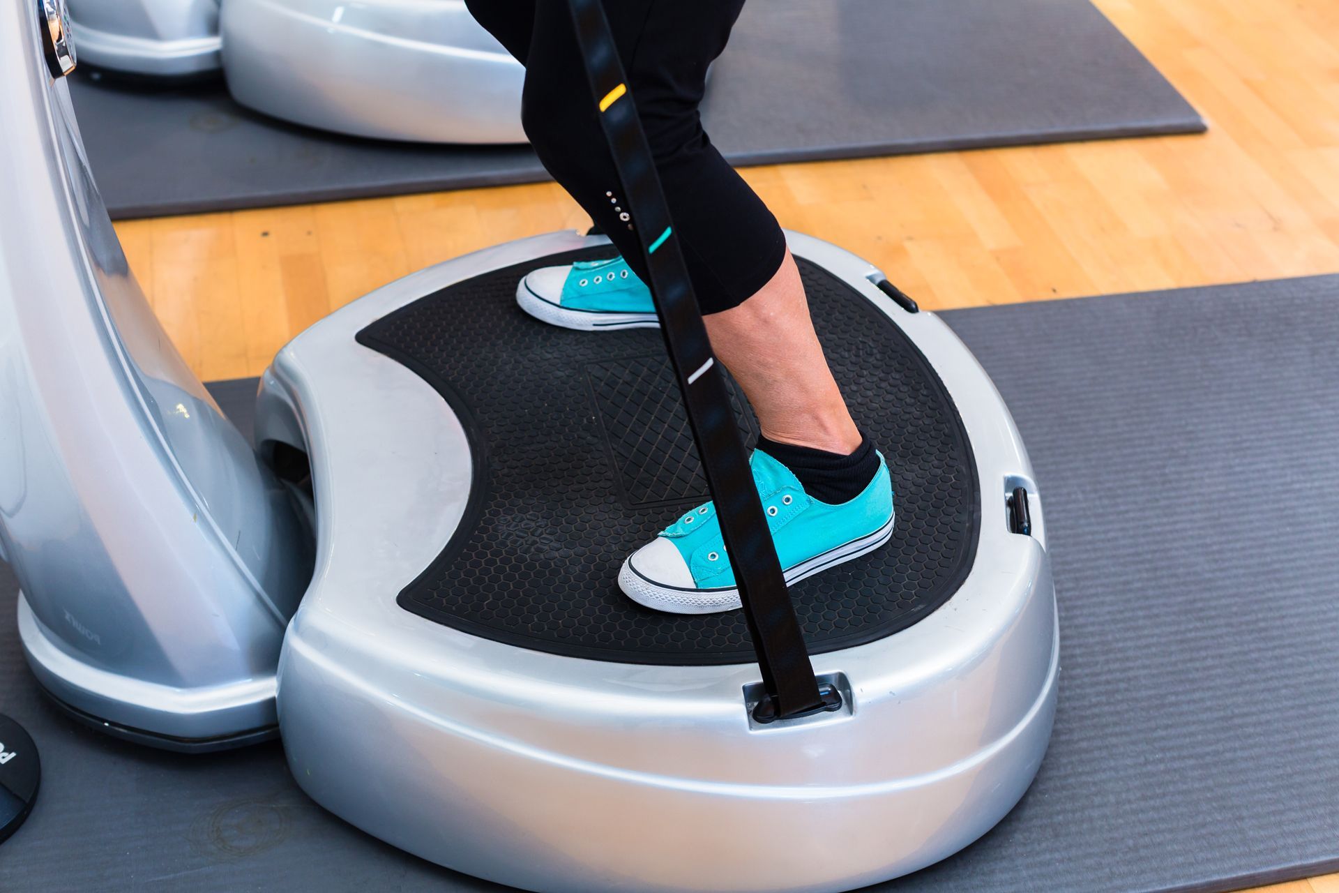 A person is using a vibration machine in a gym