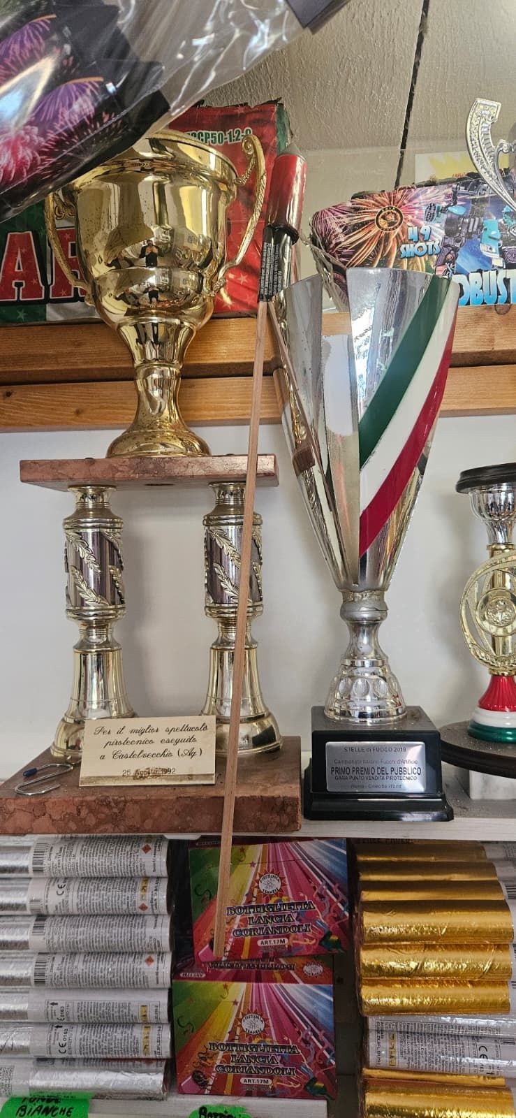 Diversi trofei su uno scaffale; il trofeo sulla destra ha i colori della bandiera italiana.