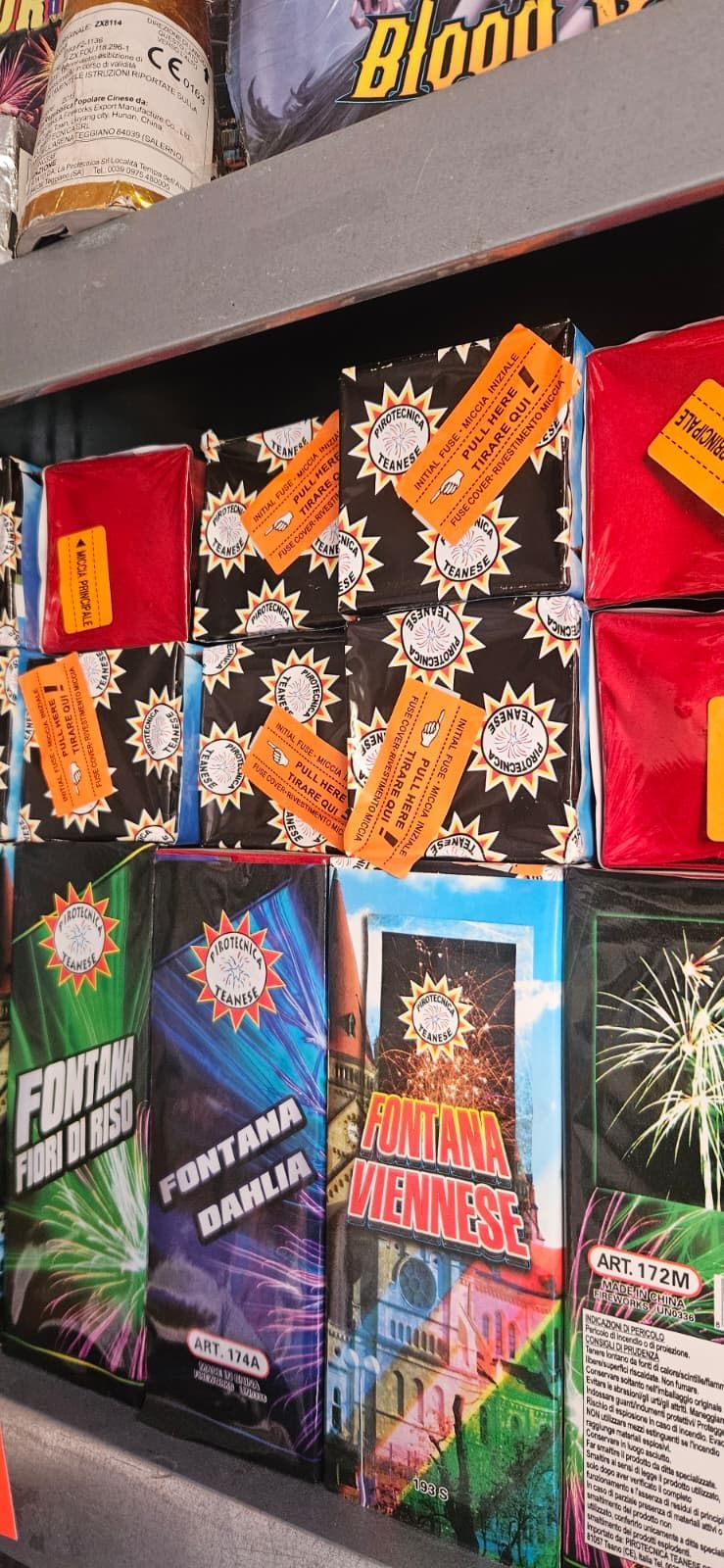 Scaffali pieni di scatole di fuochi d'artificio, di vari colori ed etichette.