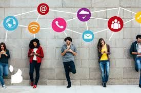 A group of people standing next to each other looking at their phones.