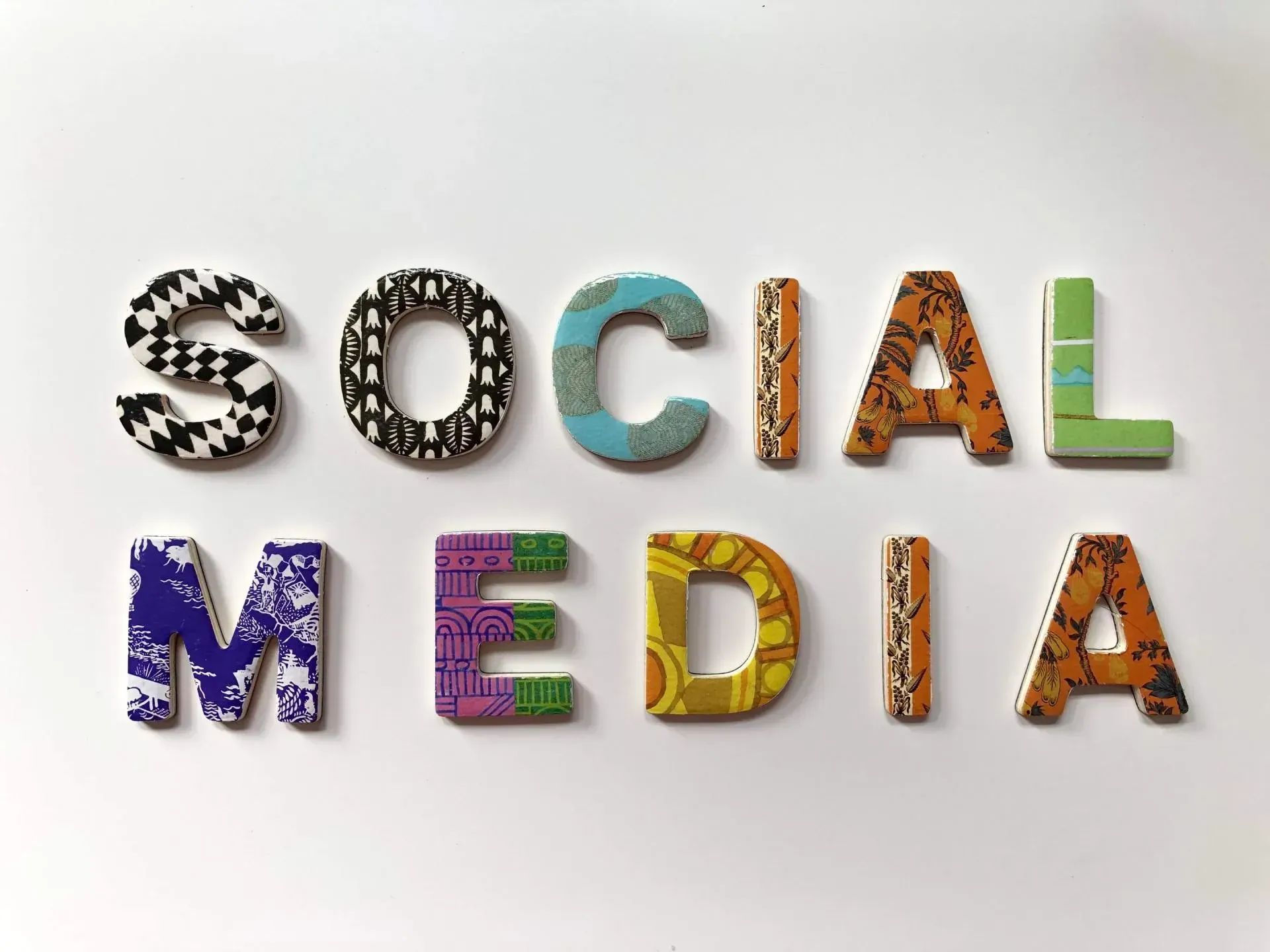 The word social media is written in colorful letters on a white surface.