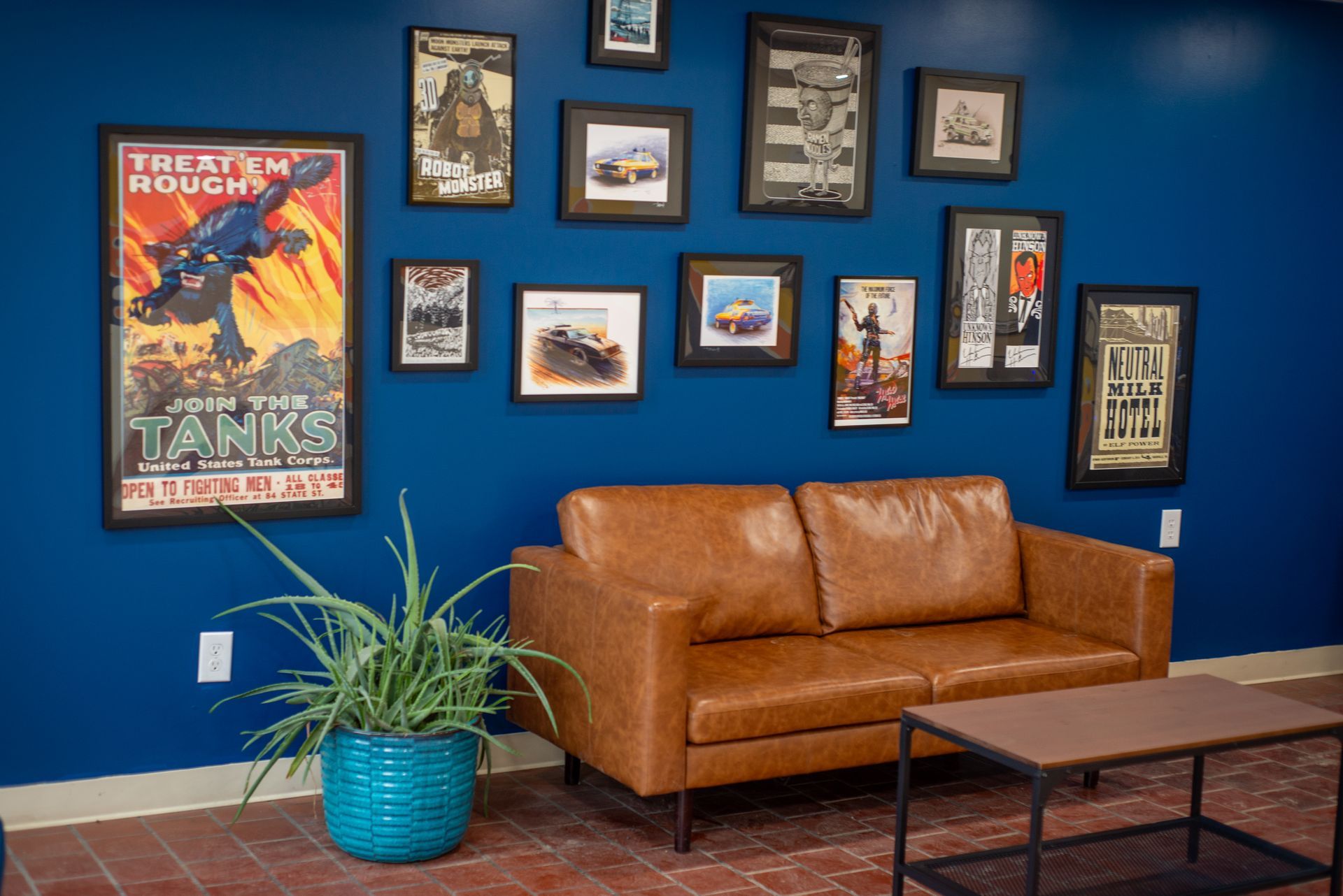 A living room with a couch , coffee table , and pictures on the wall.