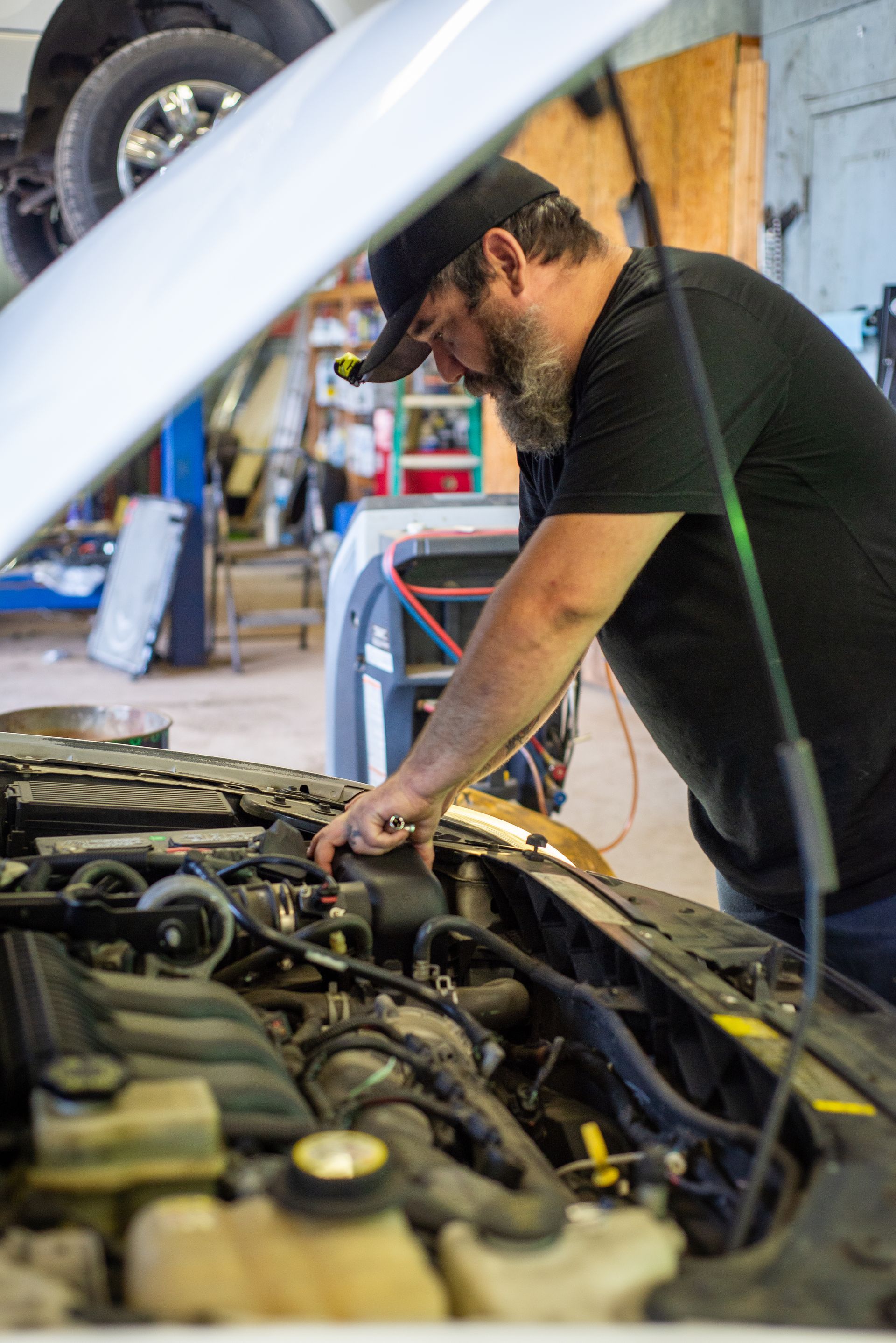 A man is working on the engine of a car in a garage.