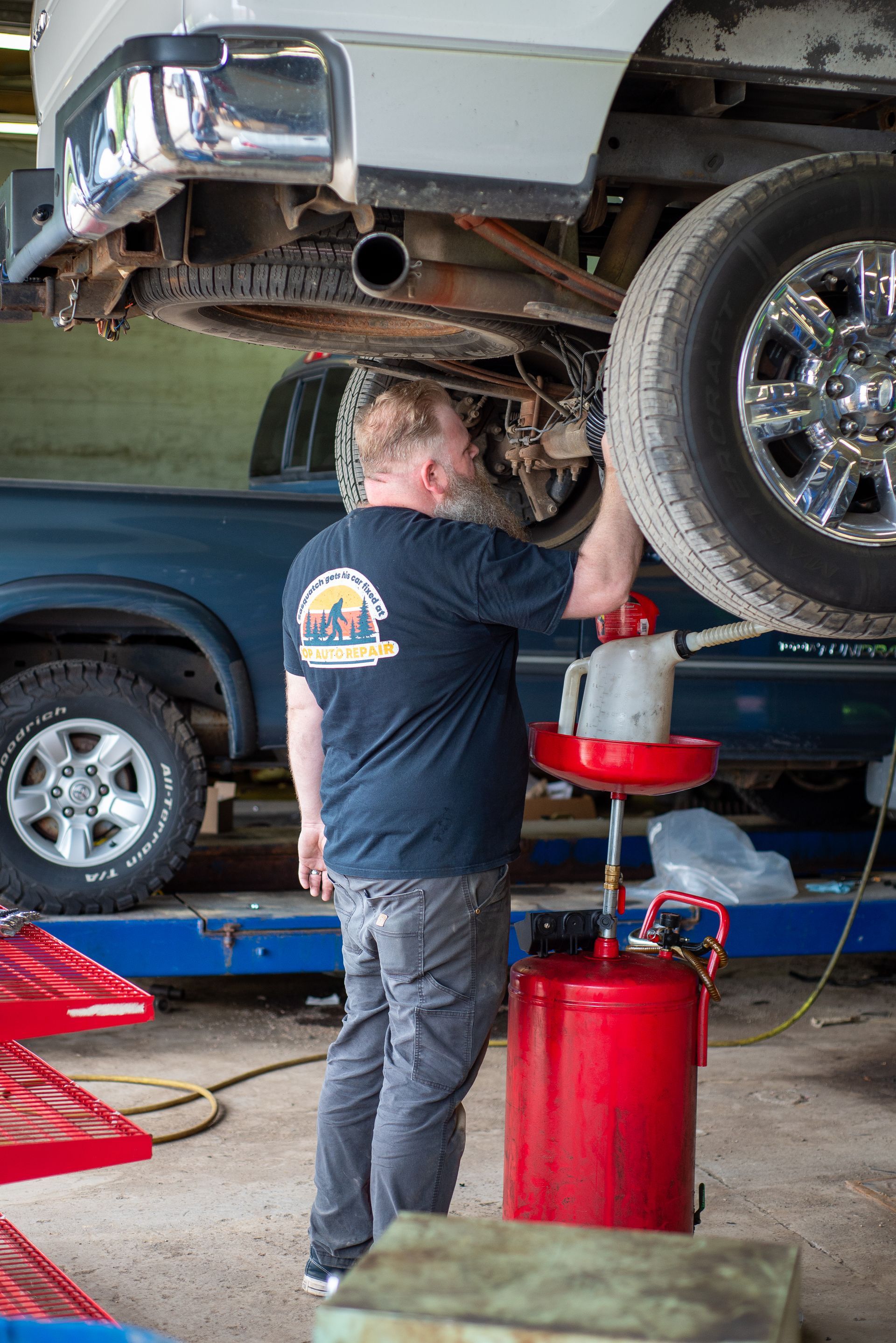 A man is working on the underside of a truck in a garage.