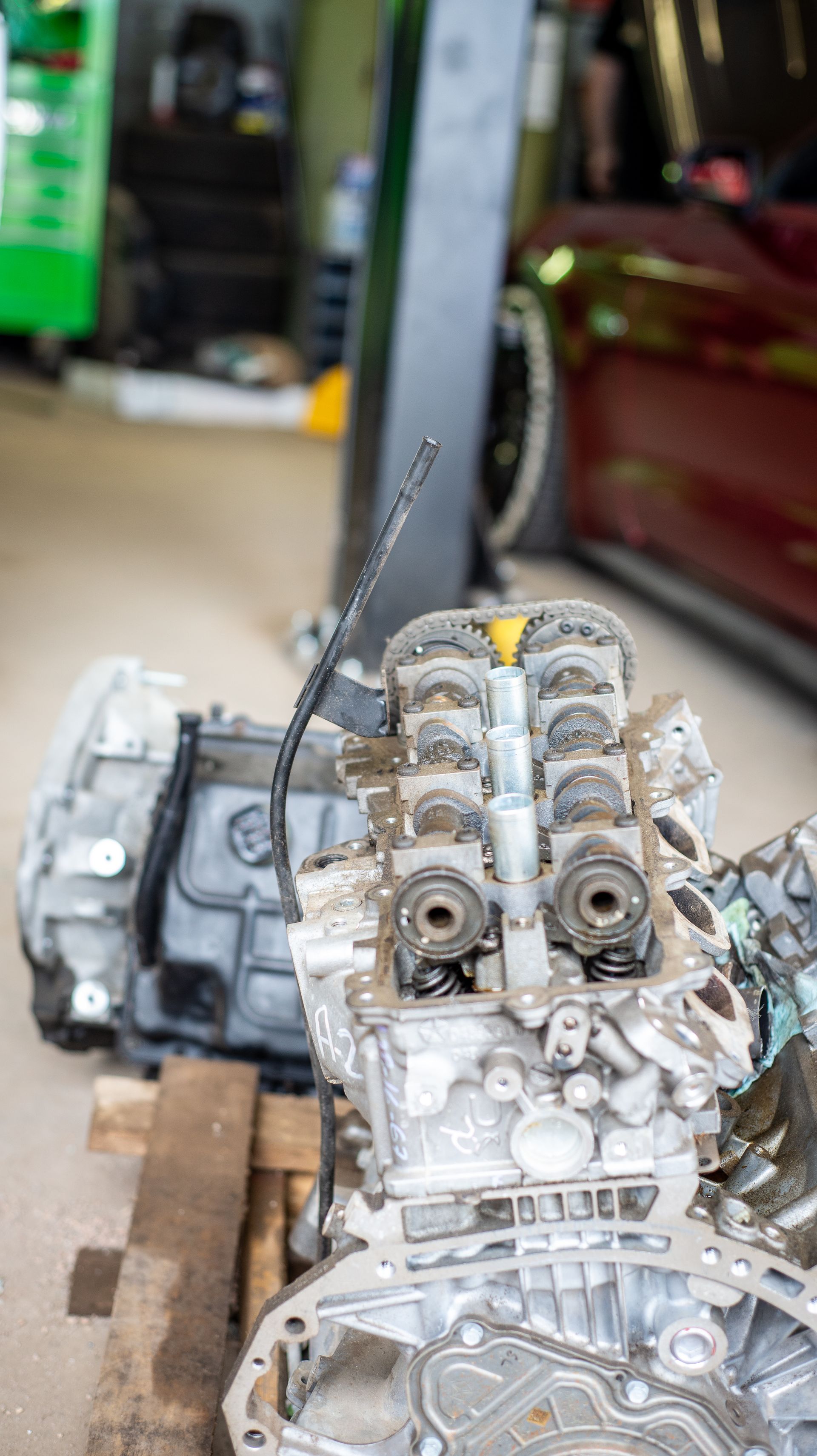 A car engine is sitting on top of a wooden pallet in a garage.