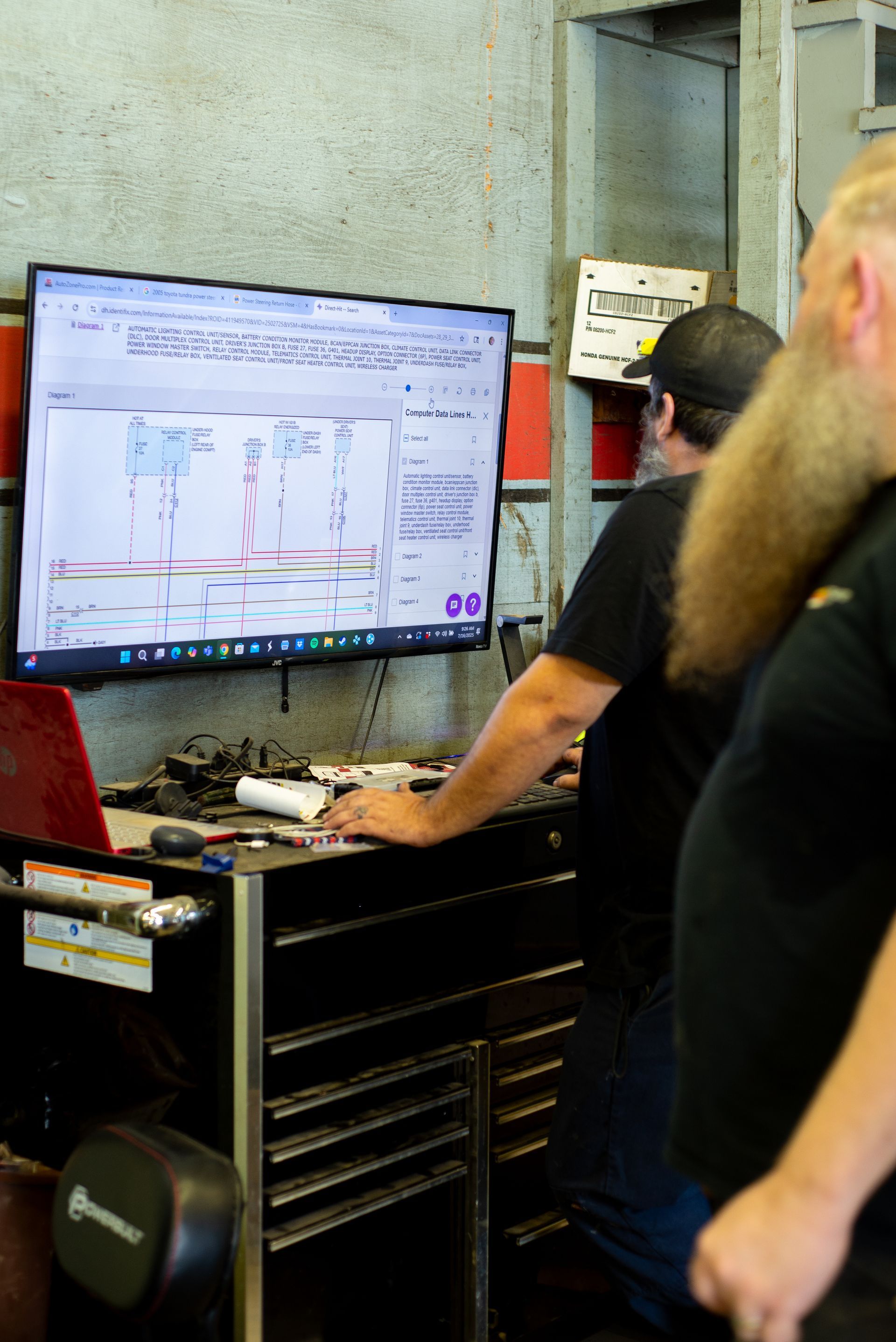 Two men are looking at a computer screen in a garage.