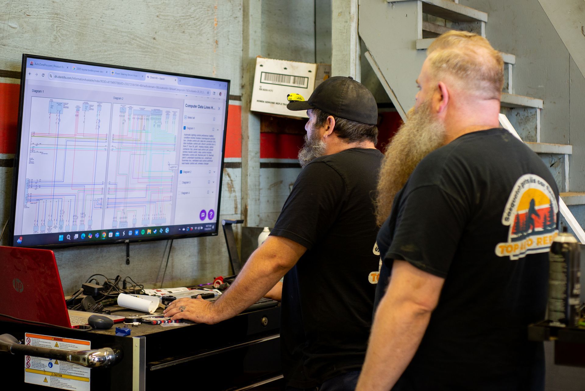 Two men are looking at a computer screen in a garage.