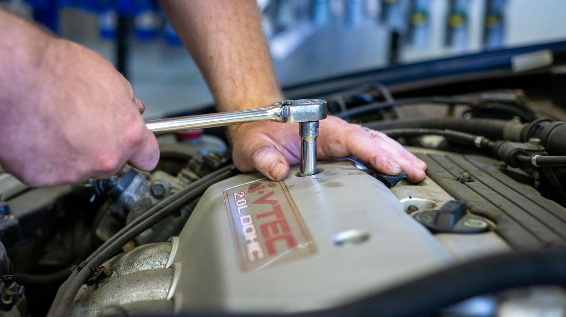 A man is working on a car engine with a wrench. | Top Auto Repair