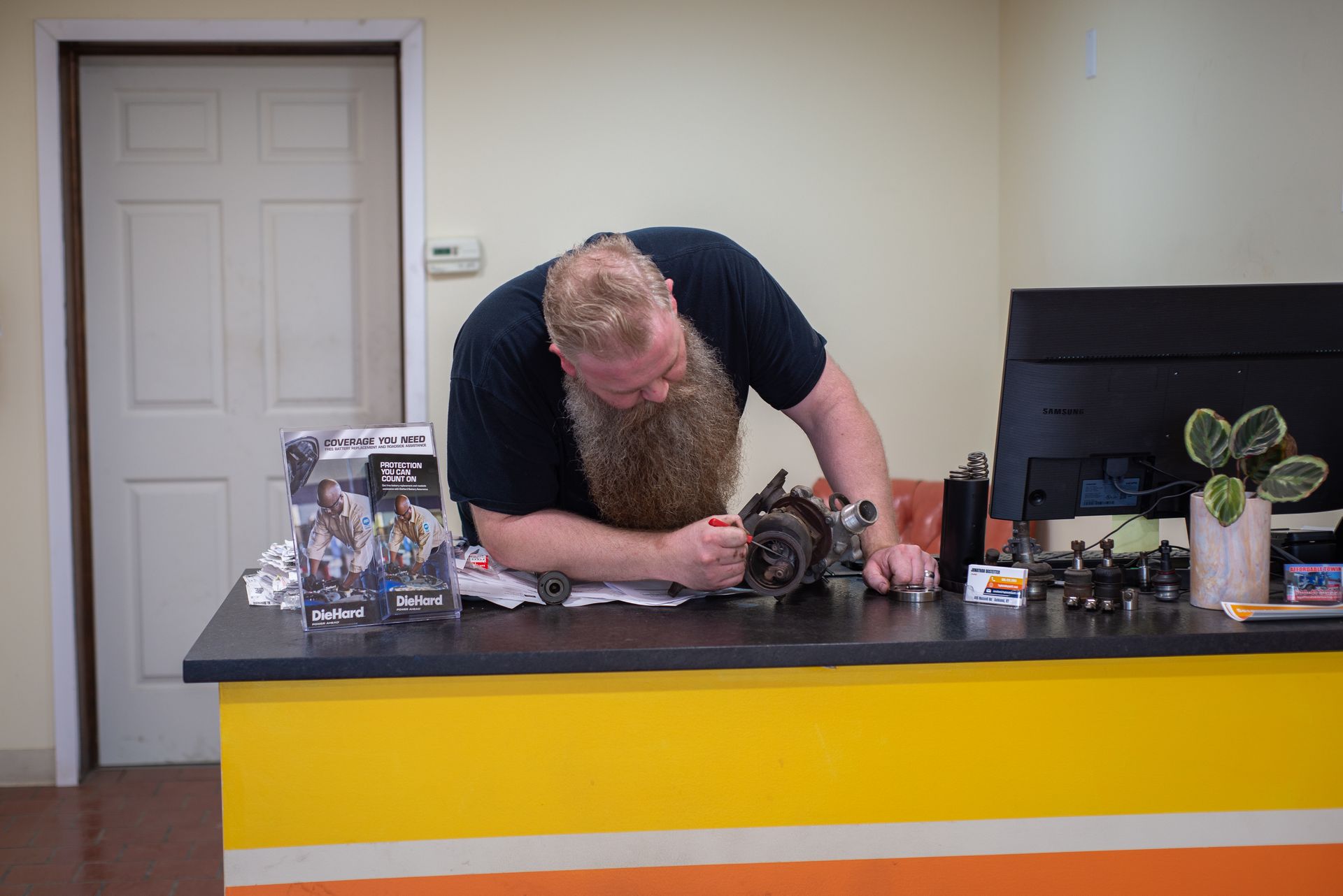 A man with a beard is working on a camera at a desk. | Top Auto Repair