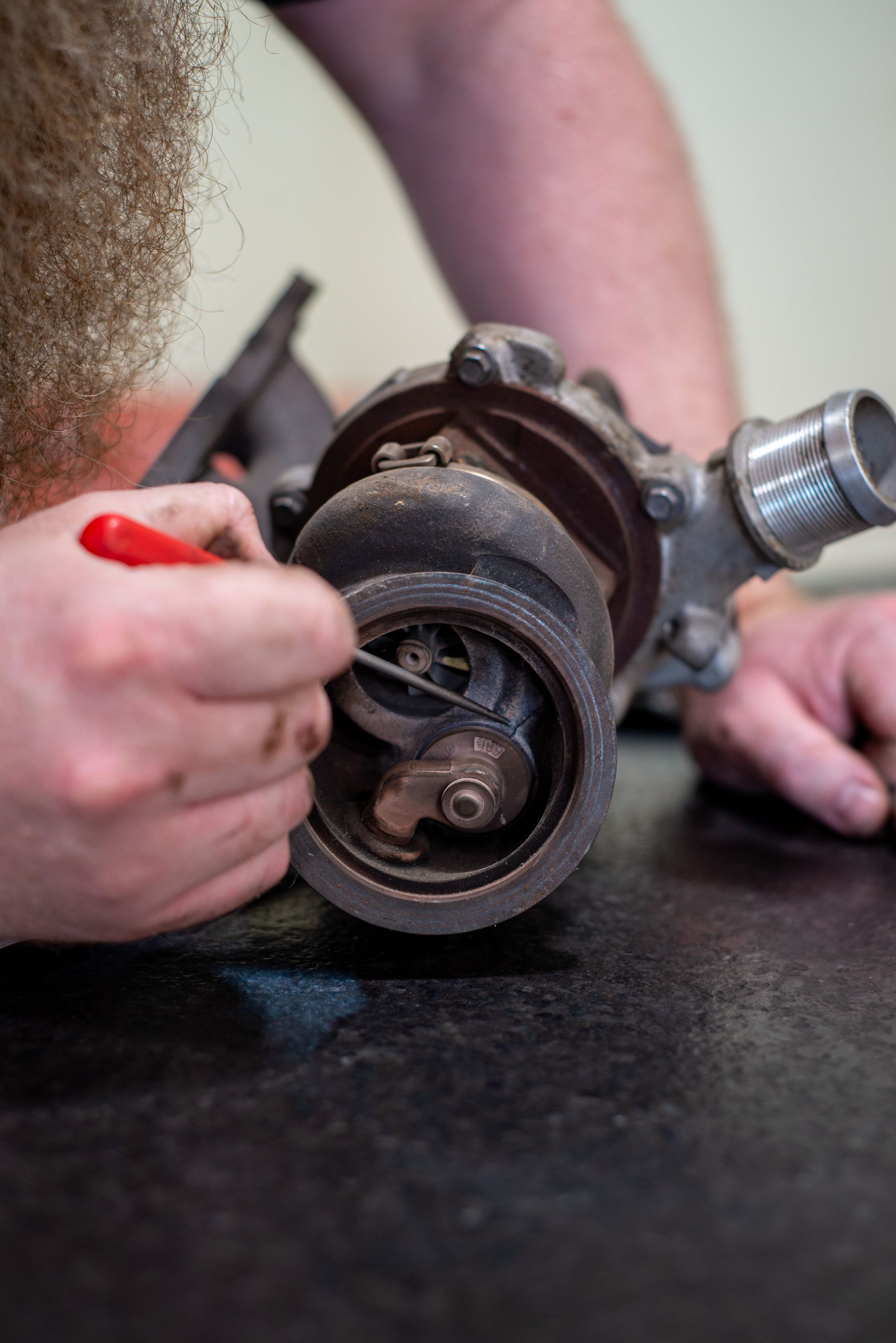 A man is working on a turbocharger with a screwdriver. | Top Auto Repair
