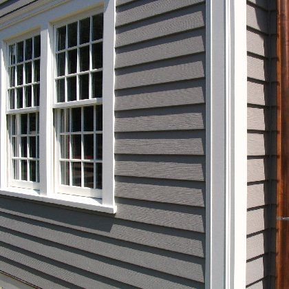 The side of a house with gray siding and white windows