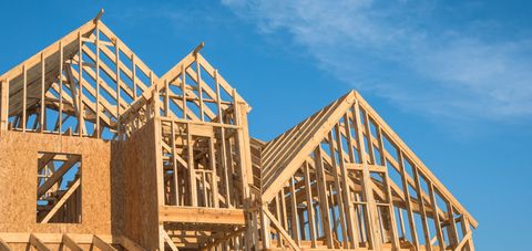 Wooden frame of a house under construction against a blue sky.