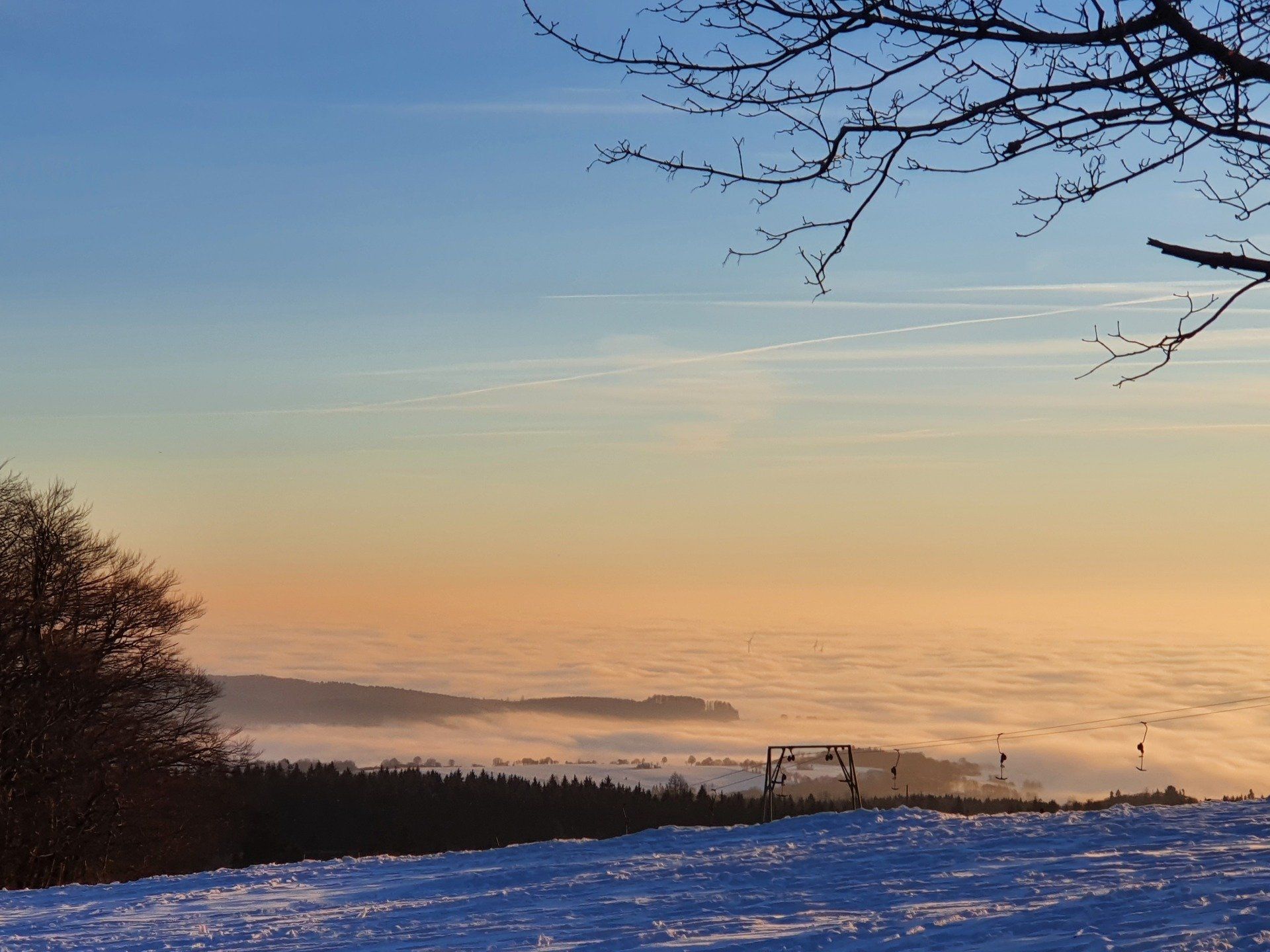 Eine verschneite Landschaft mit einem Sonnenuntergang im Hintergrund