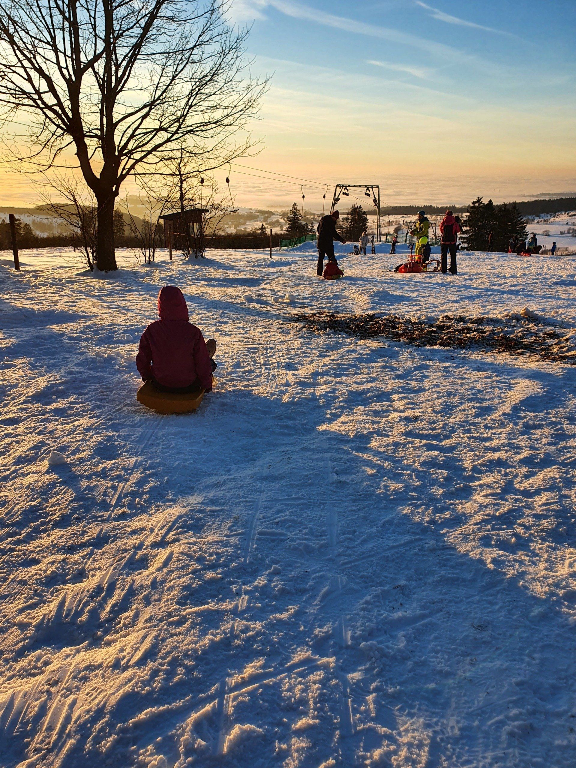 Ein Kind sitzt auf einem Schlitten im Schnee