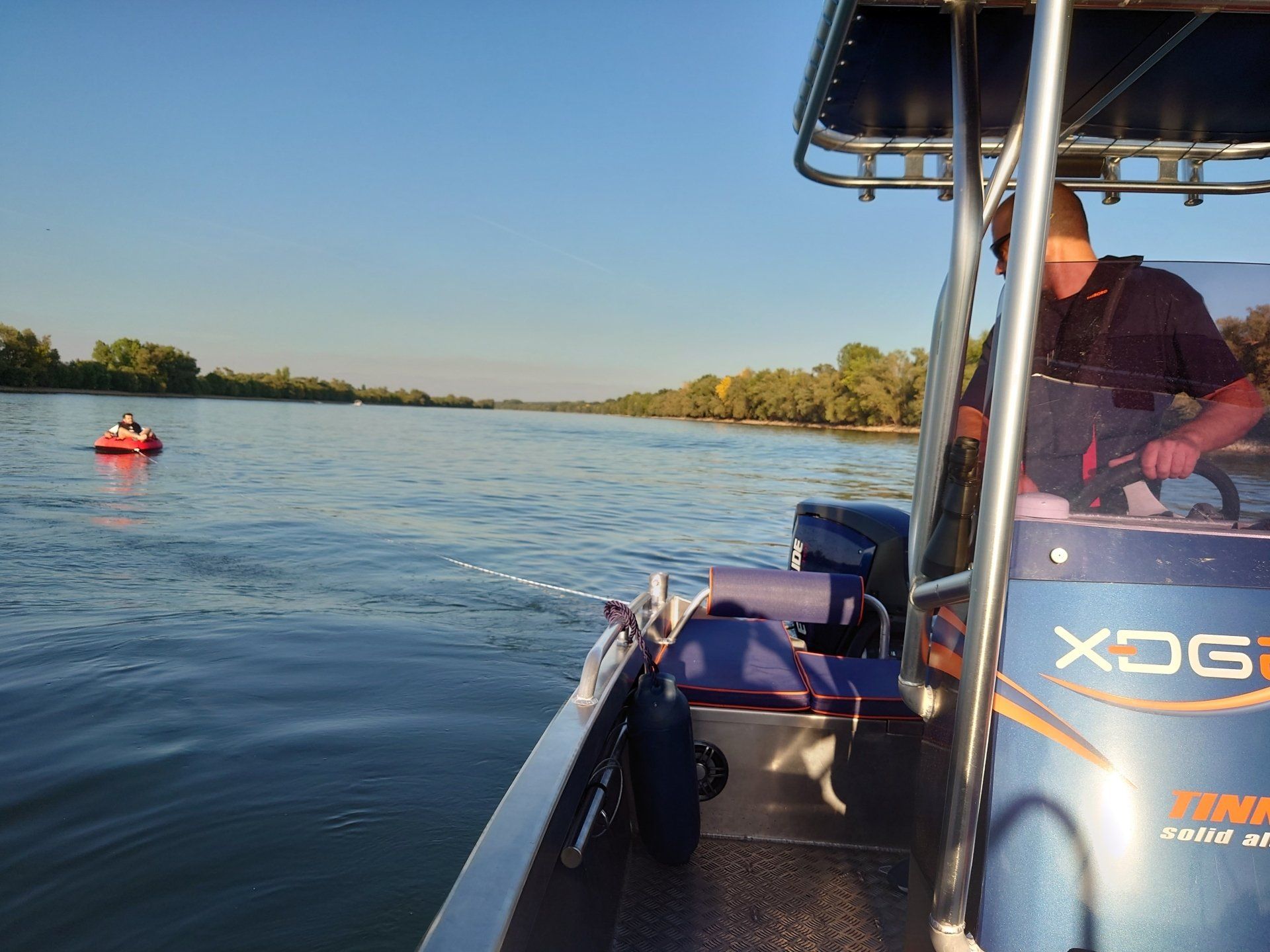 Ein Mann steuert ein Boot, auf dessen Vorderseite xdg steht