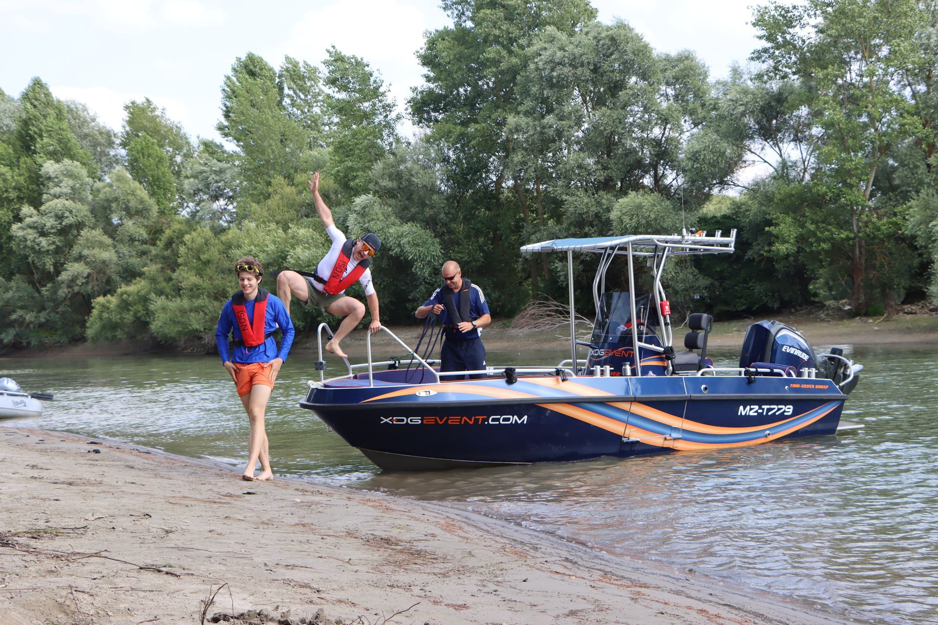 Ein Mann springt von einem Boot, auf dessen Seite hb-tpm steht