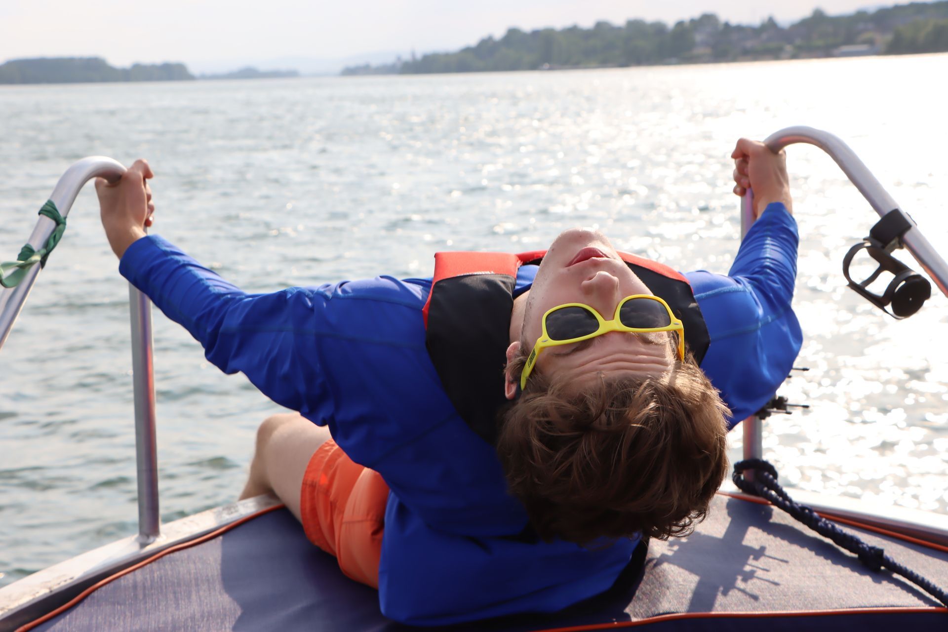 Ein Mann mit Sonnenbrille und Schwimmweste liegt auf einem Boot