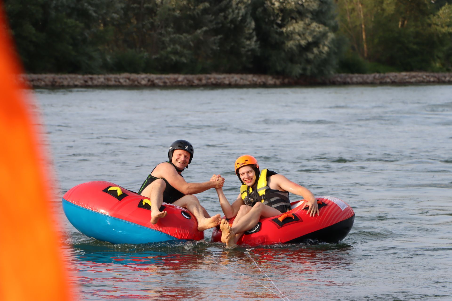Zwei Personen sitzen auf Schläuchen im Wasser und geben sich gegenseitig ein High Five