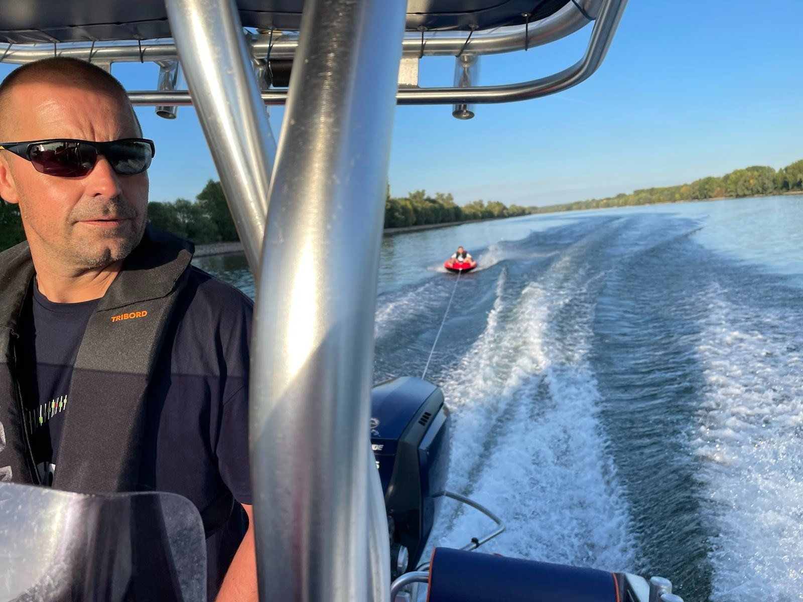 Ein Mann mit Sonnenbrille sitzt auf einem Boot im Wasser