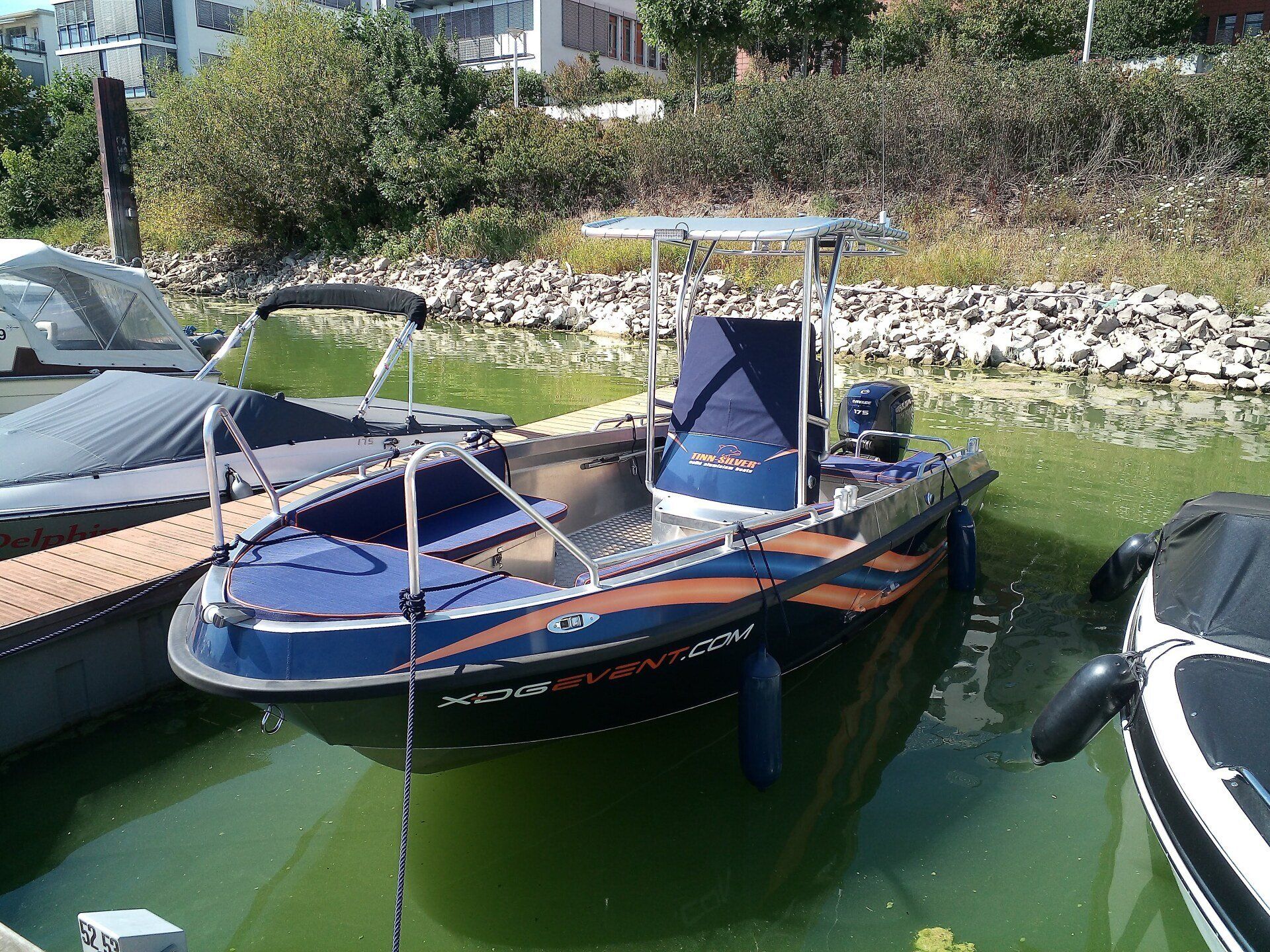 Ein blau-orangefarbenes Boot liegt in einem Gewässer angedockt