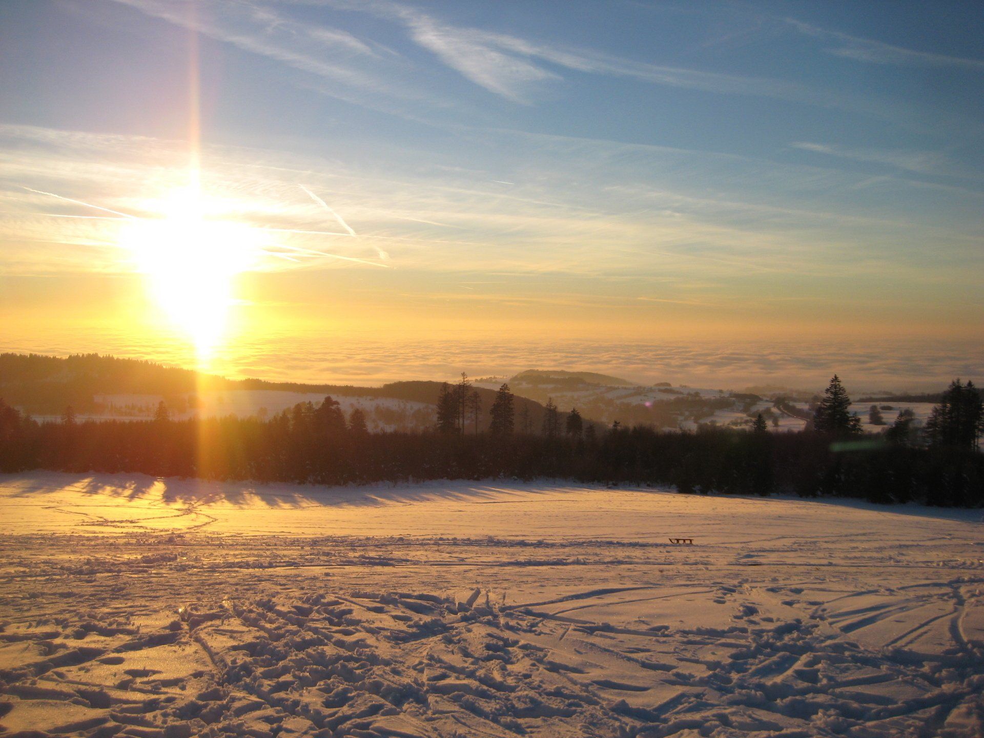 Die Sonne geht über einem schneebedeckten Feld unter