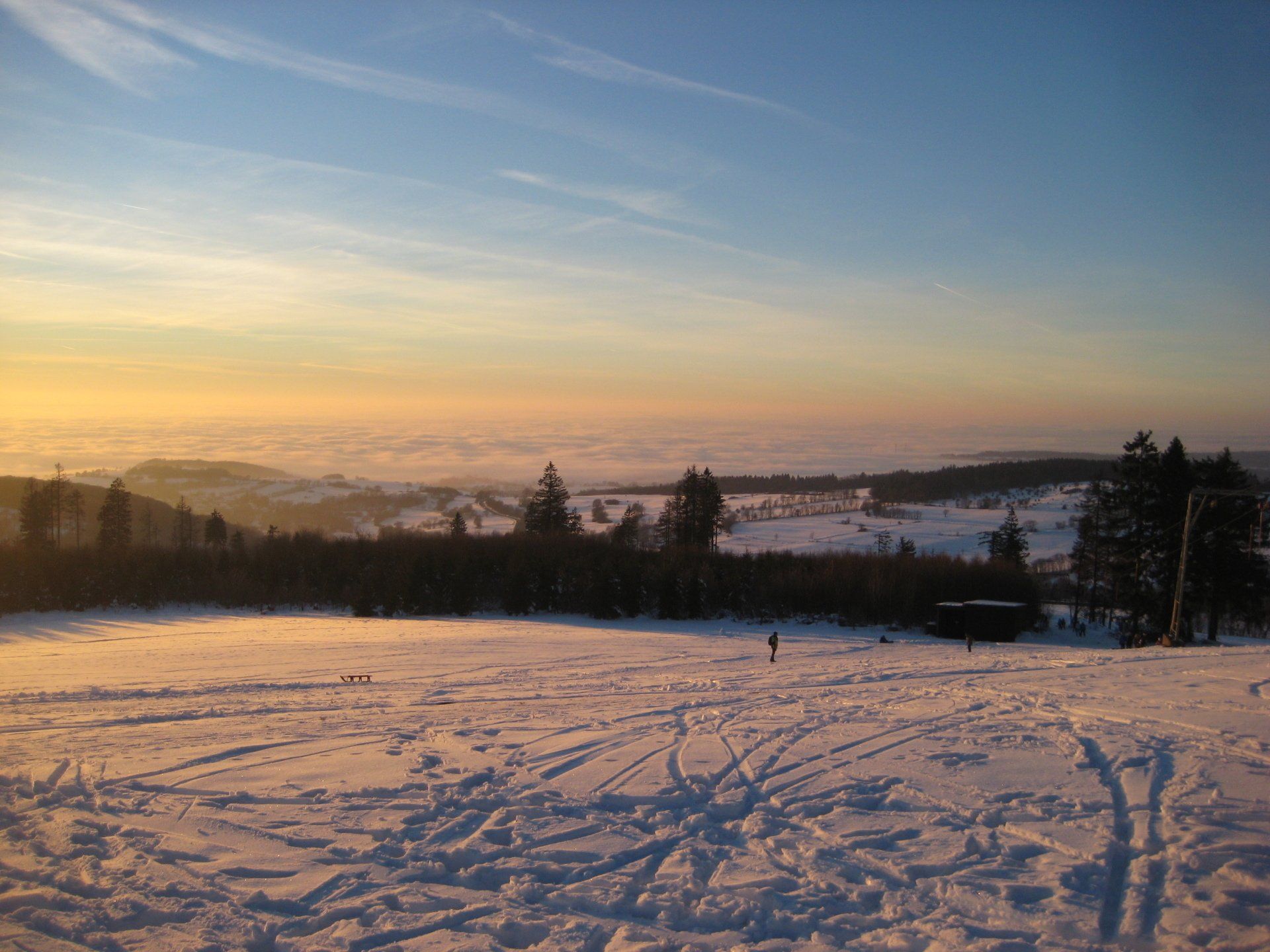 Ein schneebedecktes Feld mit einem Sonnenuntergang im Hintergrund