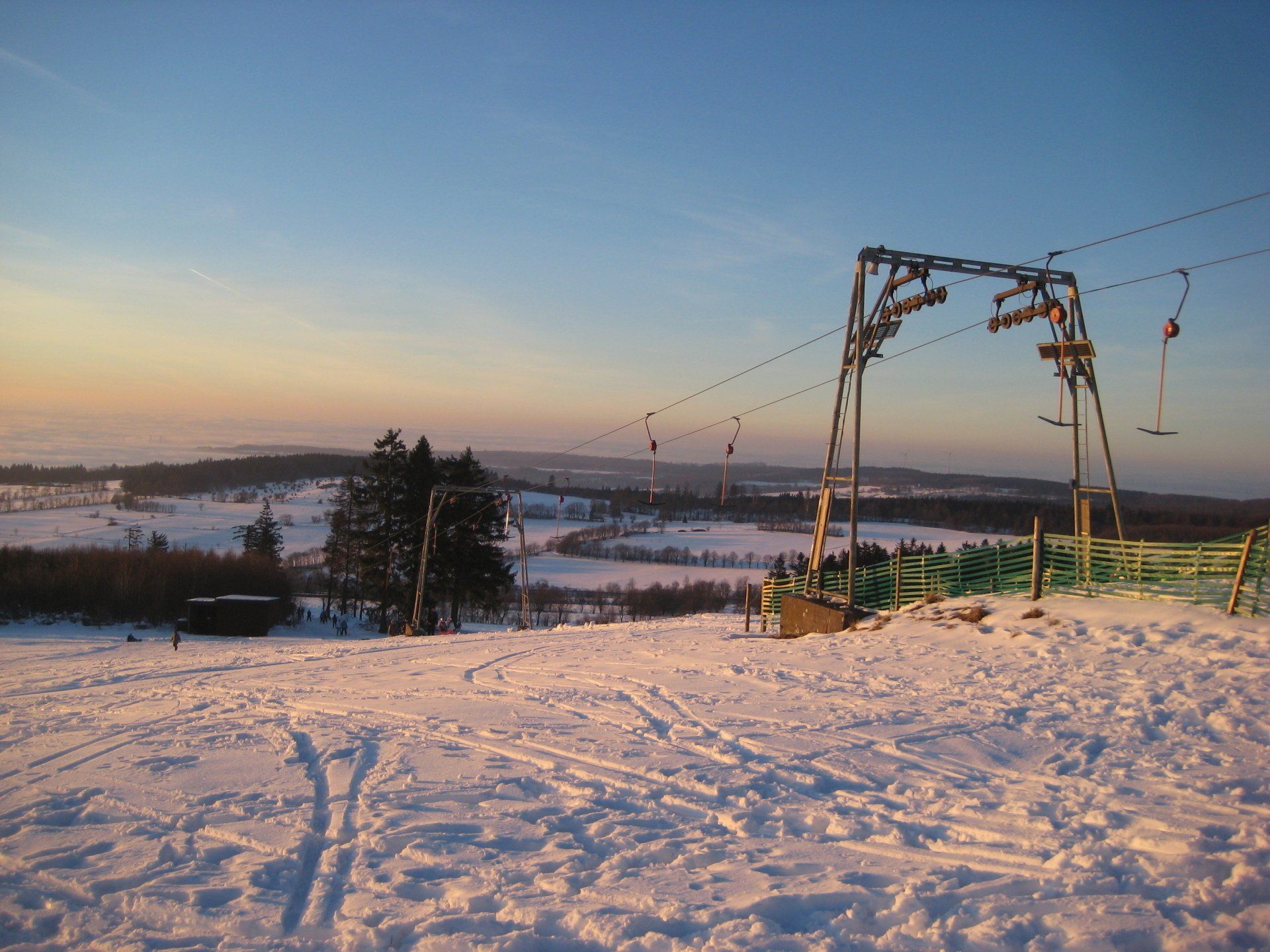Eine verschneite Landschaft mit einem Skilift im Vordergrund