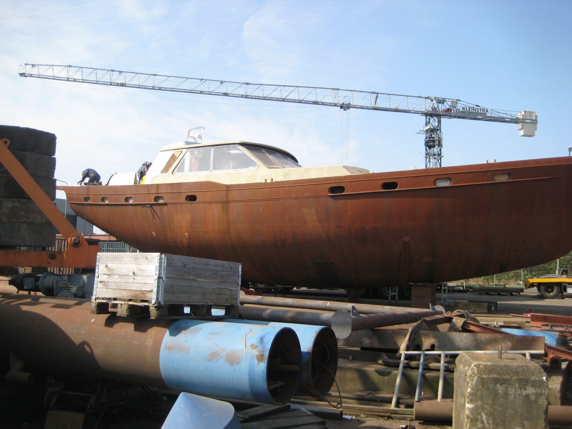 Ein rostiges Boot liegt in einem Dock mit einem Kran im Hintergrund