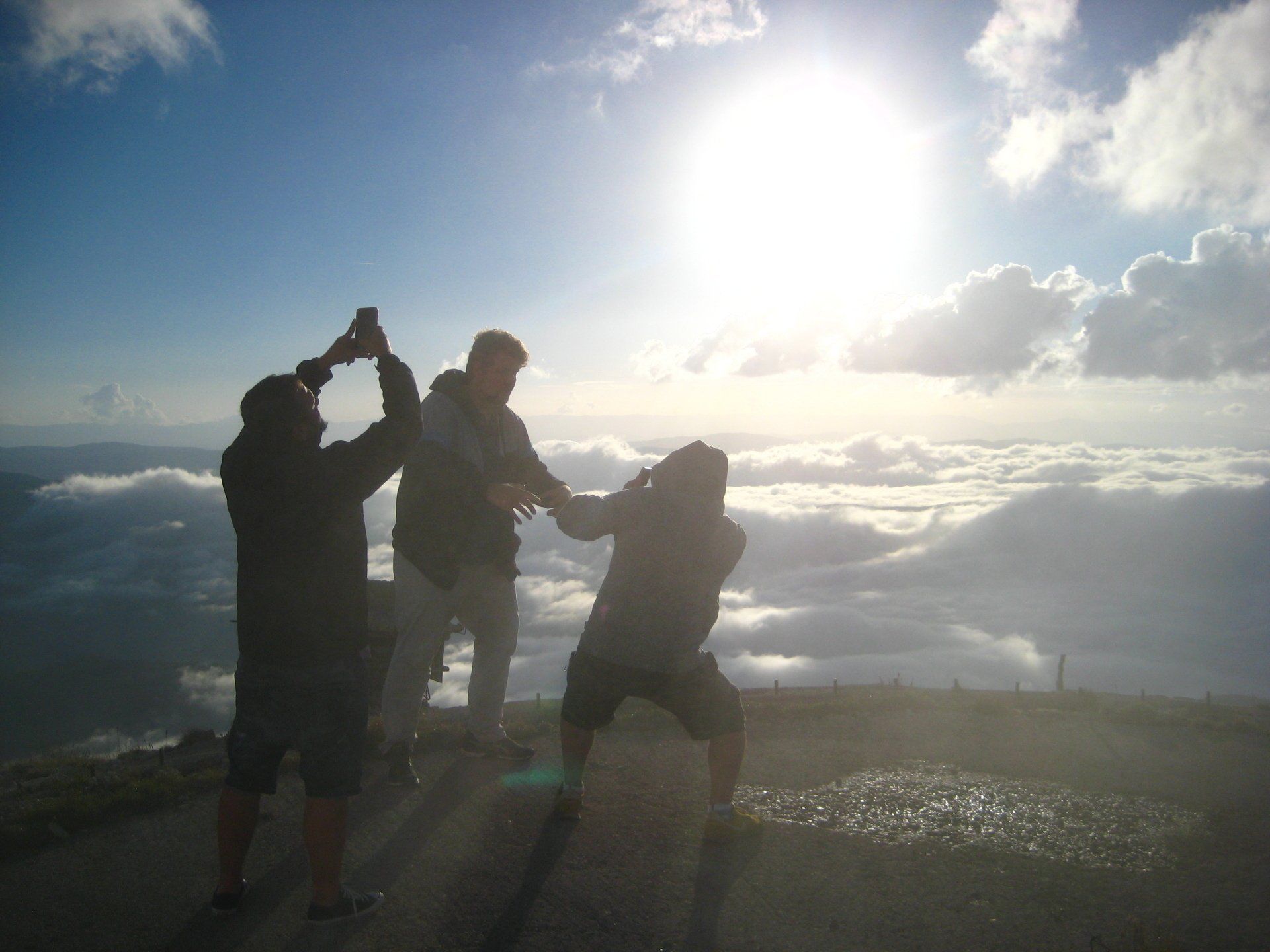 Eine Gruppe von Menschen steht auf einem Hügel und die Sonne scheint durch die Wolken