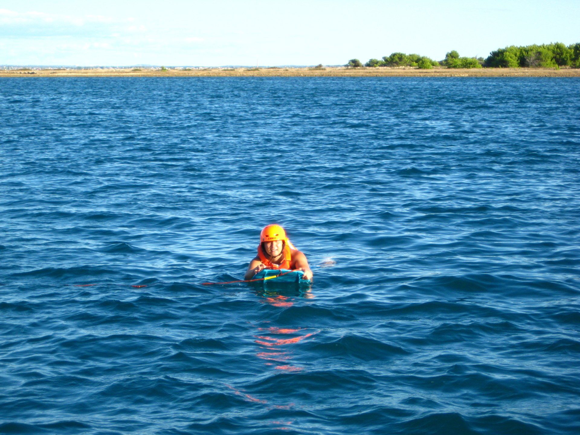 Eine Person mit einem orangefarbenen Helm schwimmt im Wasser