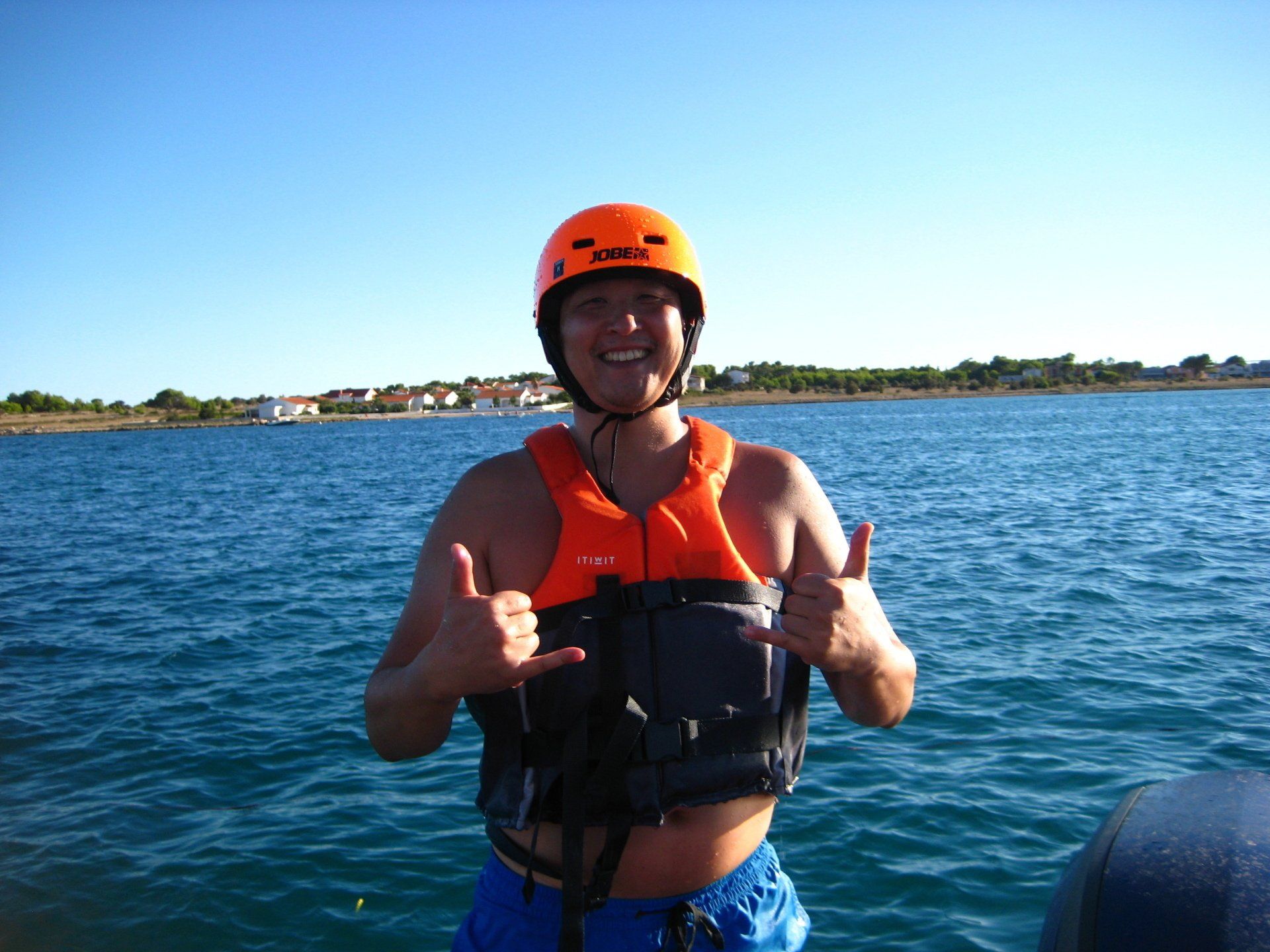 Ein Mann mit Schwimmweste und orangefarbenem Helm zeigt den Daumen nach oben