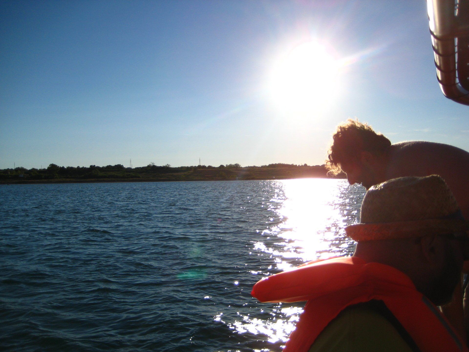 Eine Person mit einer orangefarbenen Schwimmweste blickt auf ein Gewässer