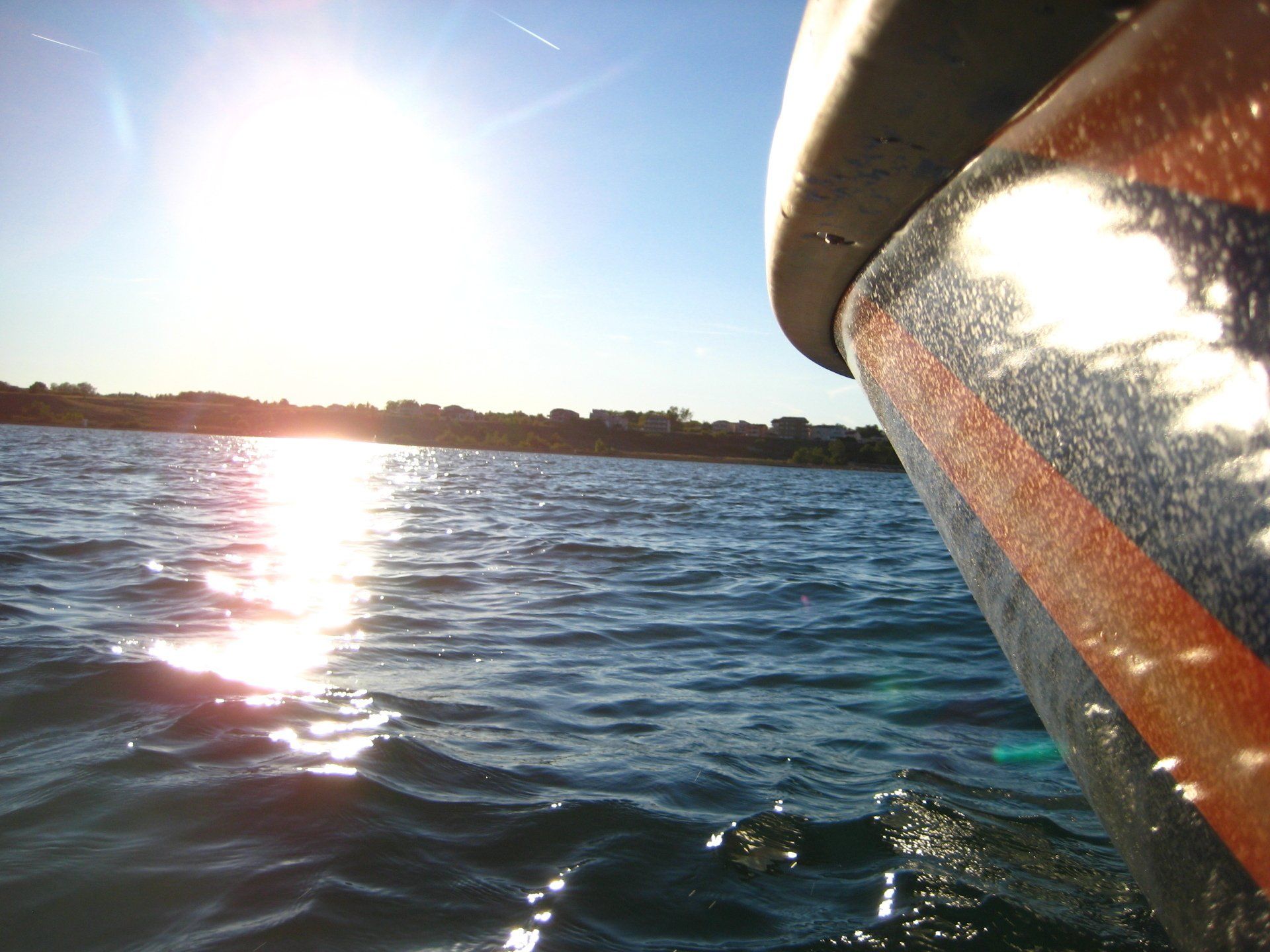 Die Sonne spiegelt sich im Wasser hinter einem Boot