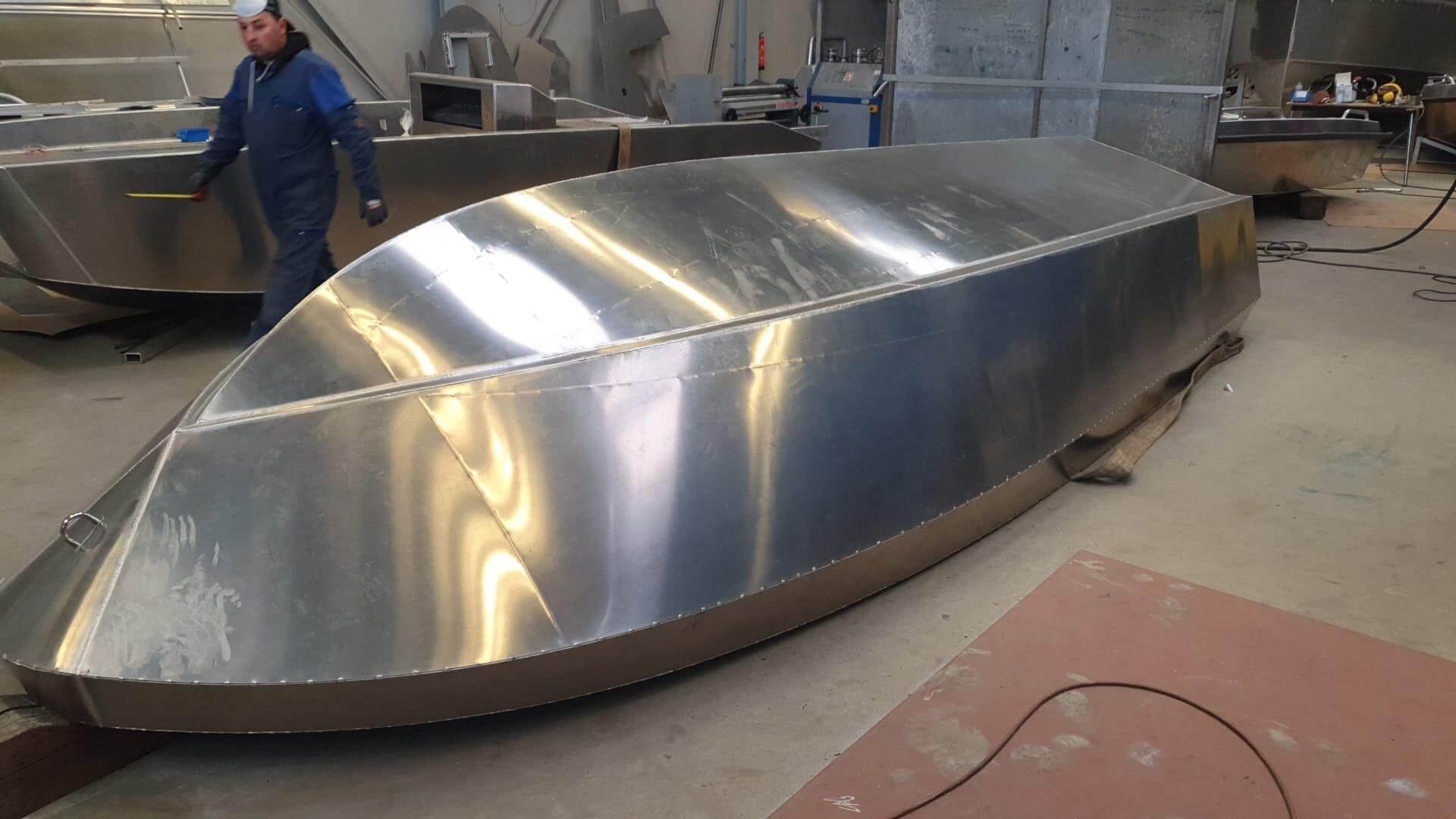 Ein Mann steht neben einem großen Aluminiumboot