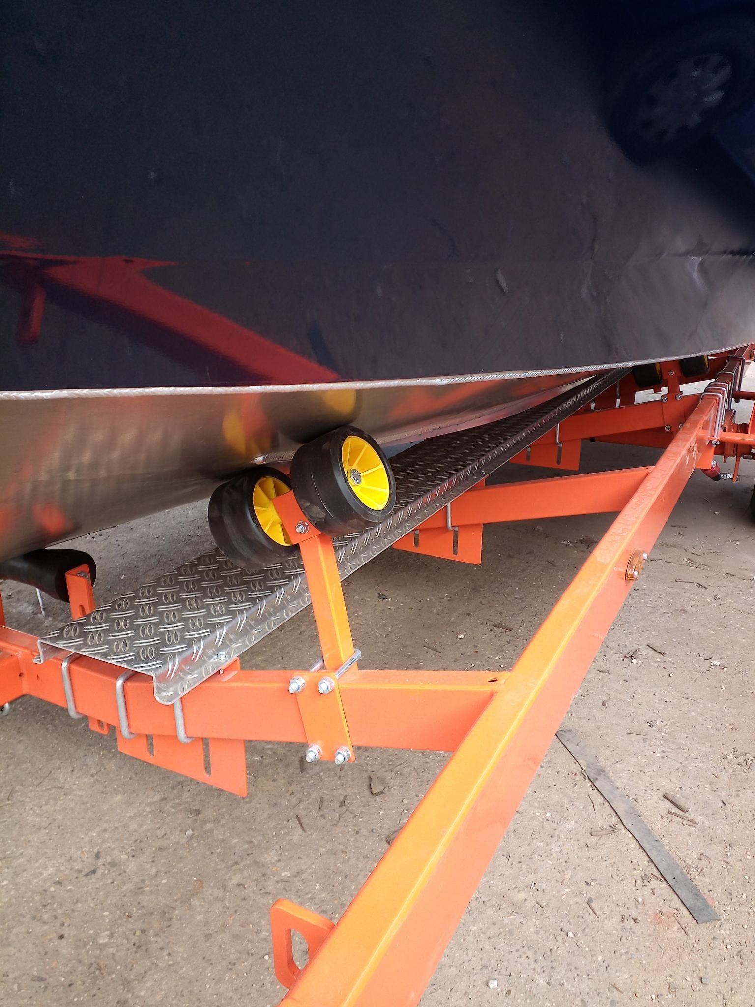 Ein Boot liegt auf einem orangefarbenen Anhänger mit gelben Rädern