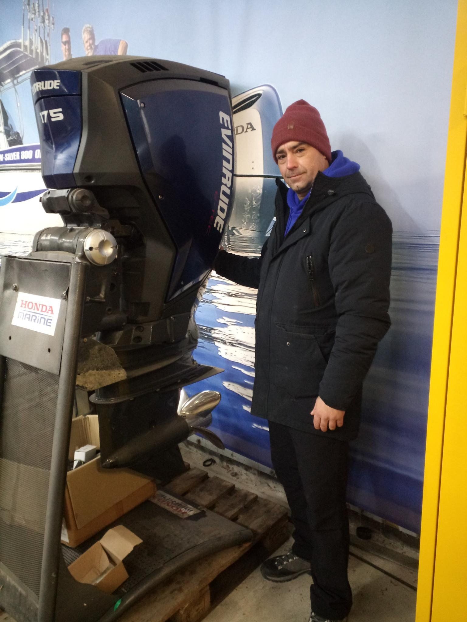 Ein Mann steht neben einem Evinrude-Außenbordmotor