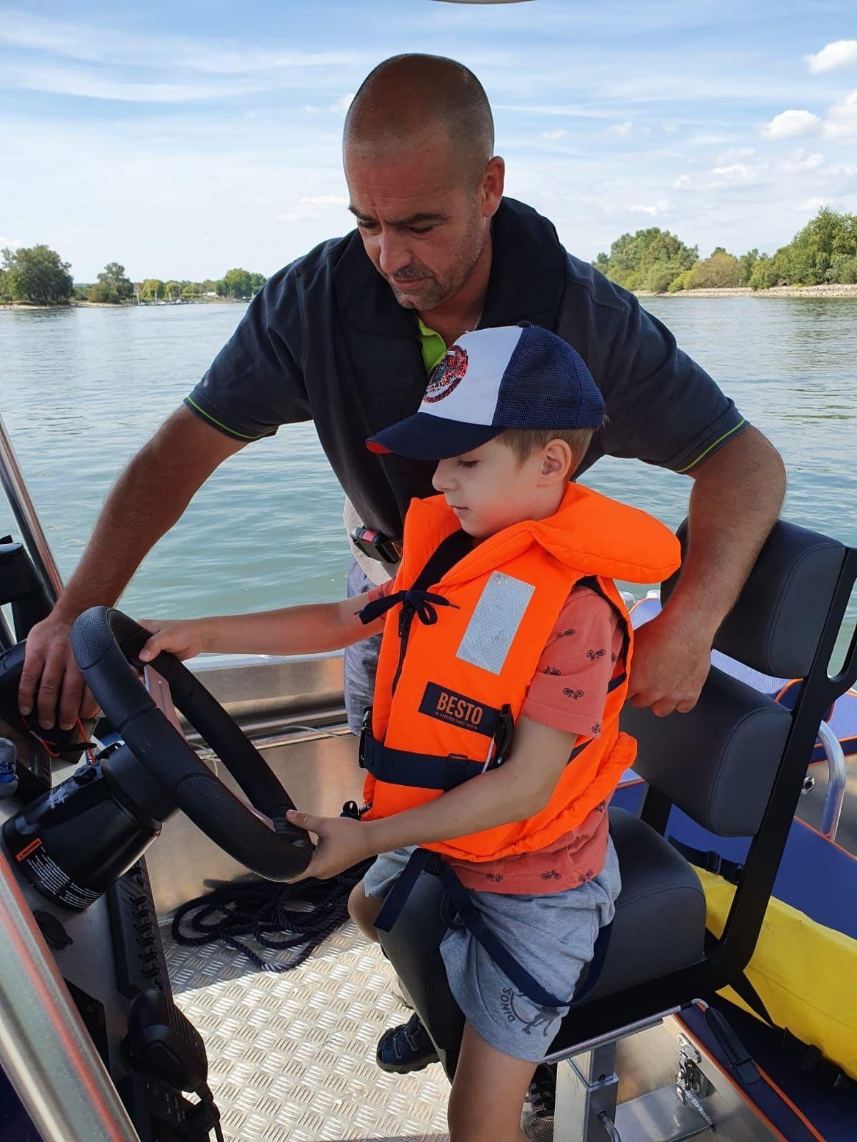 Ein Mann bringt einem kleinen Jungen das Steuern eines Bootes bei