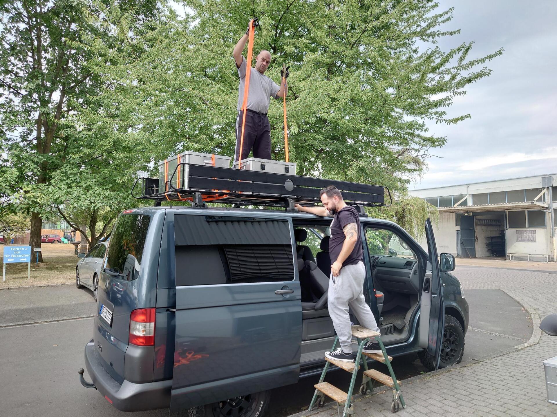 Zwei Männer arbeiten auf dem Dach eines Lieferwagens