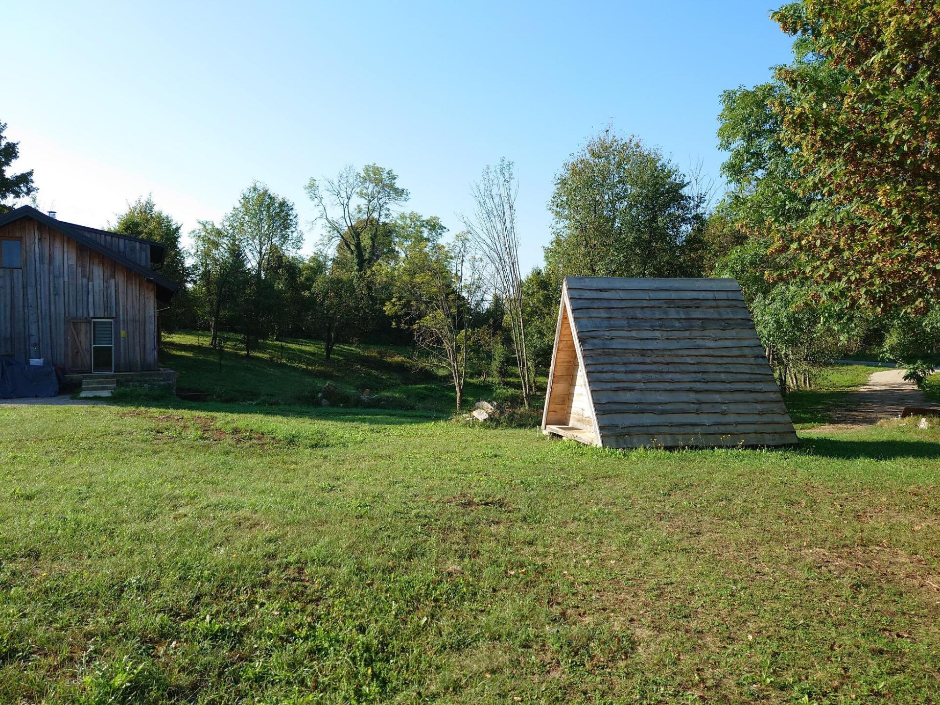 Ein Holzschuppen steht mitten auf einer Wiese