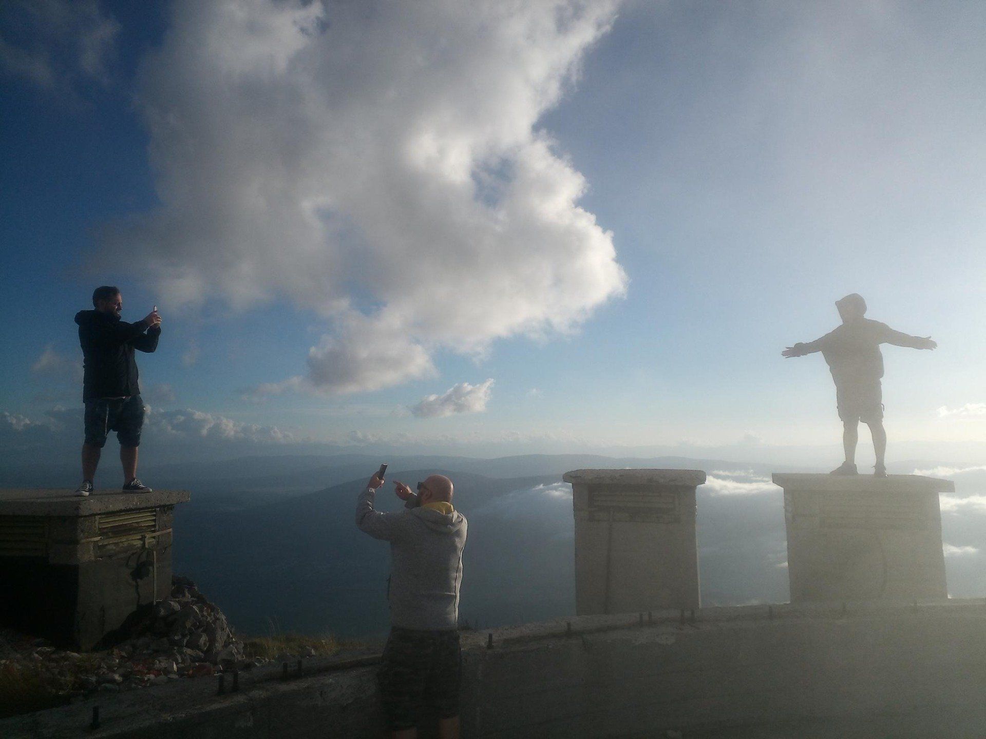 Ein paar Leute stehen mit ausgestreckten Armen auf einem Felsvorsprung
