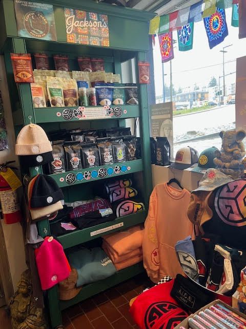 A retail display shelf filled with merchandise like snacks, beanies, and apparel, with colorful flags hanging above.
