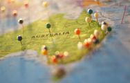 A map of Australia marked with many small, colorful pushpins, viewed from an angled perspective with shallow focus.