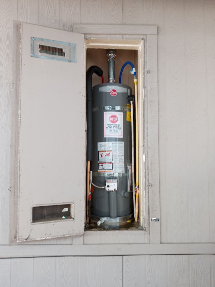 A water heater is sitting inside of a wall with the door open.
