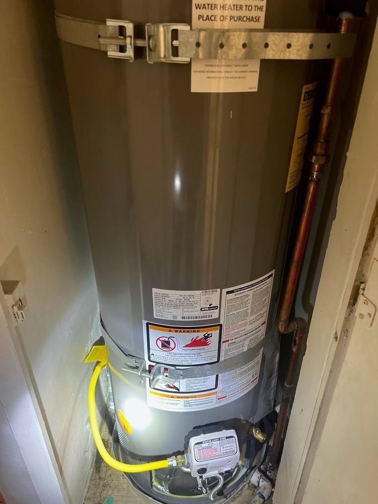 A water heater is sitting in a closet next to a door.
