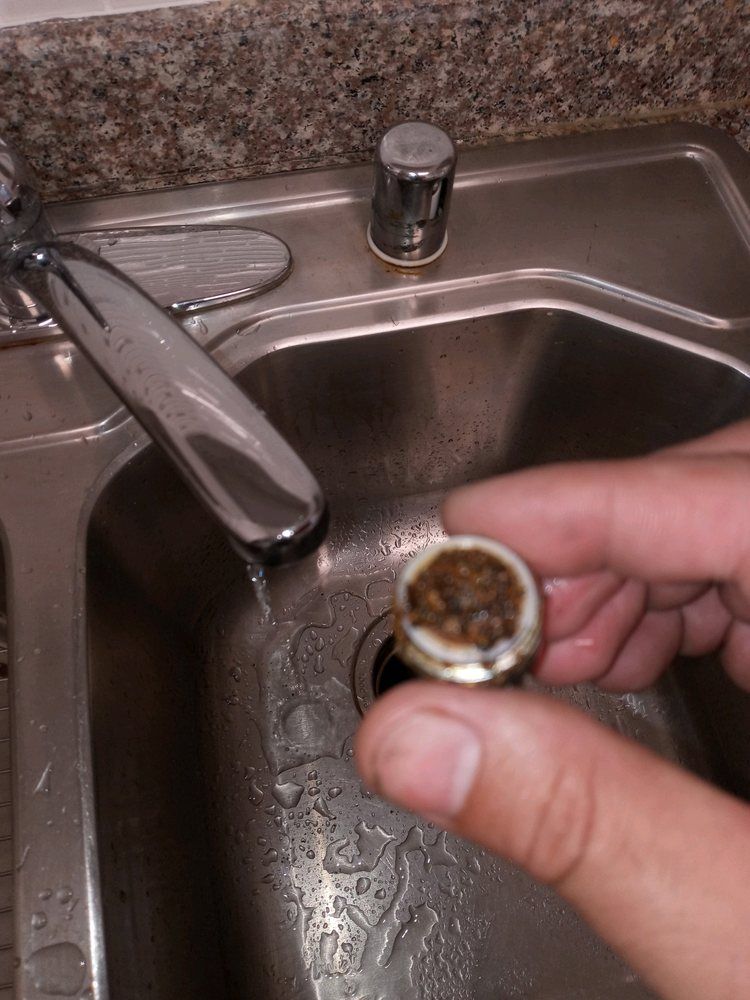 A person is holding a piece of metal in front of a sink