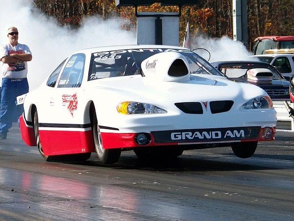 A white and red grand am racing car on a track